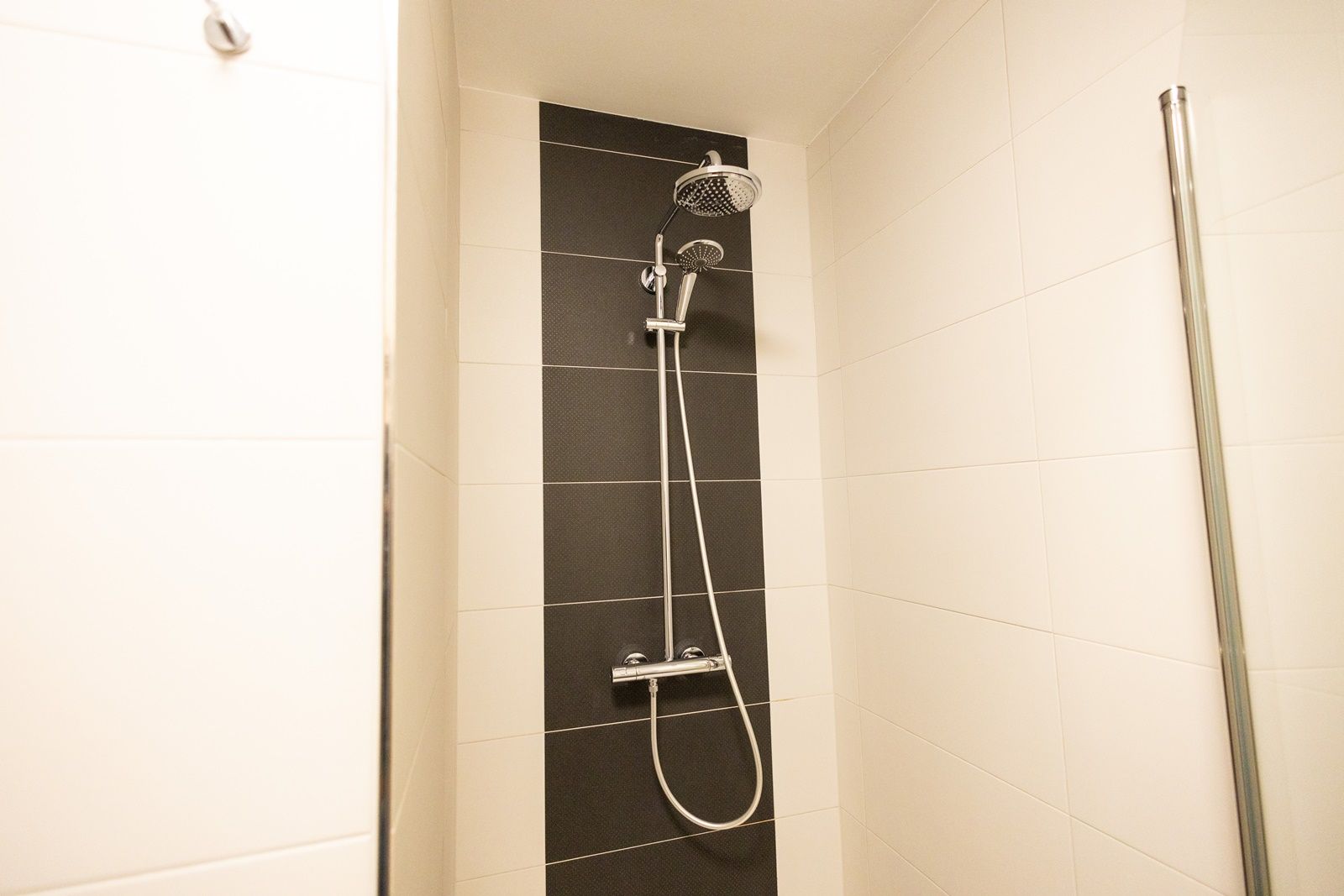 Modern shower with black and white tiled wall.