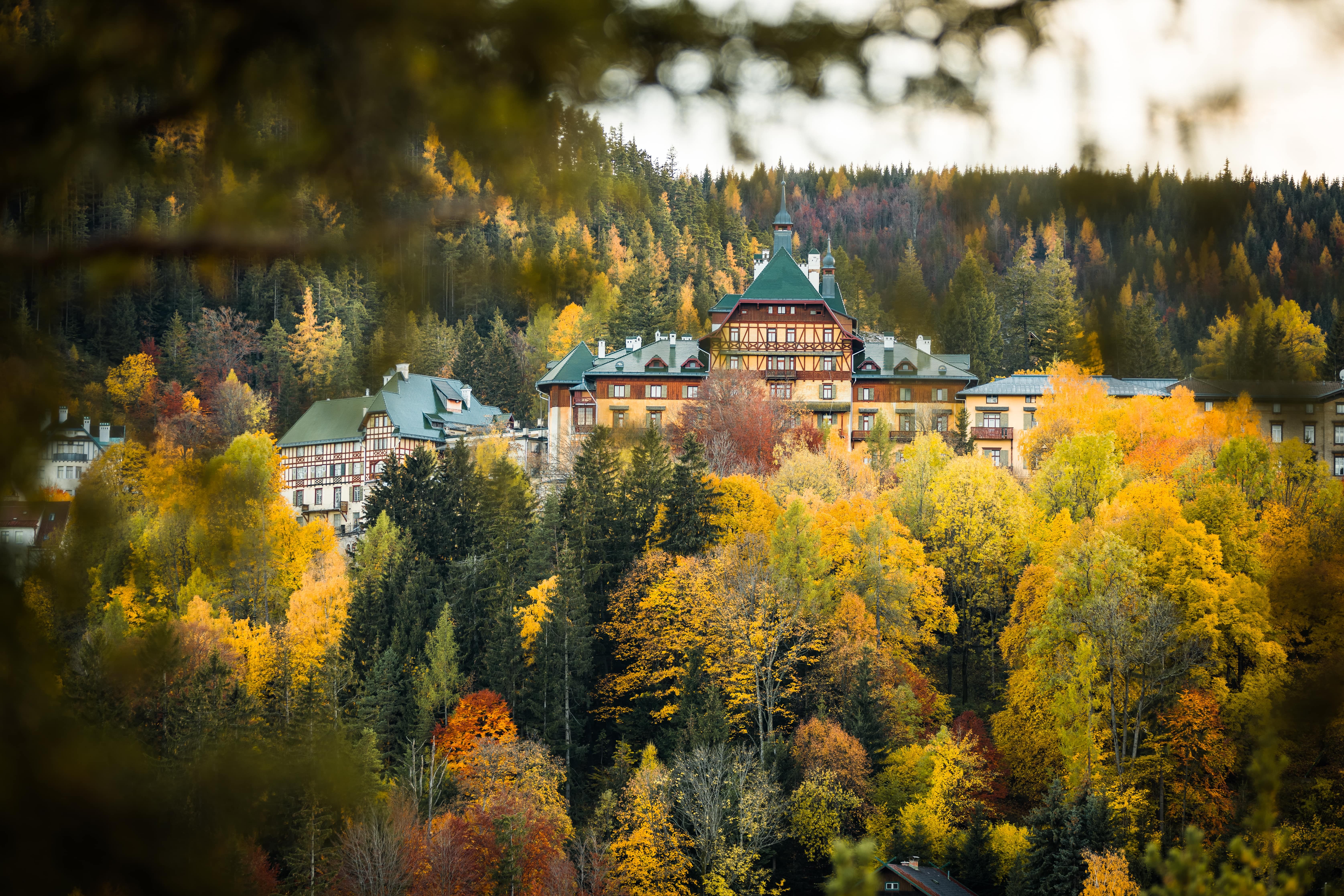 Südbahnhotel Semmering in autumn, surrounded by colorful deciduous forest.