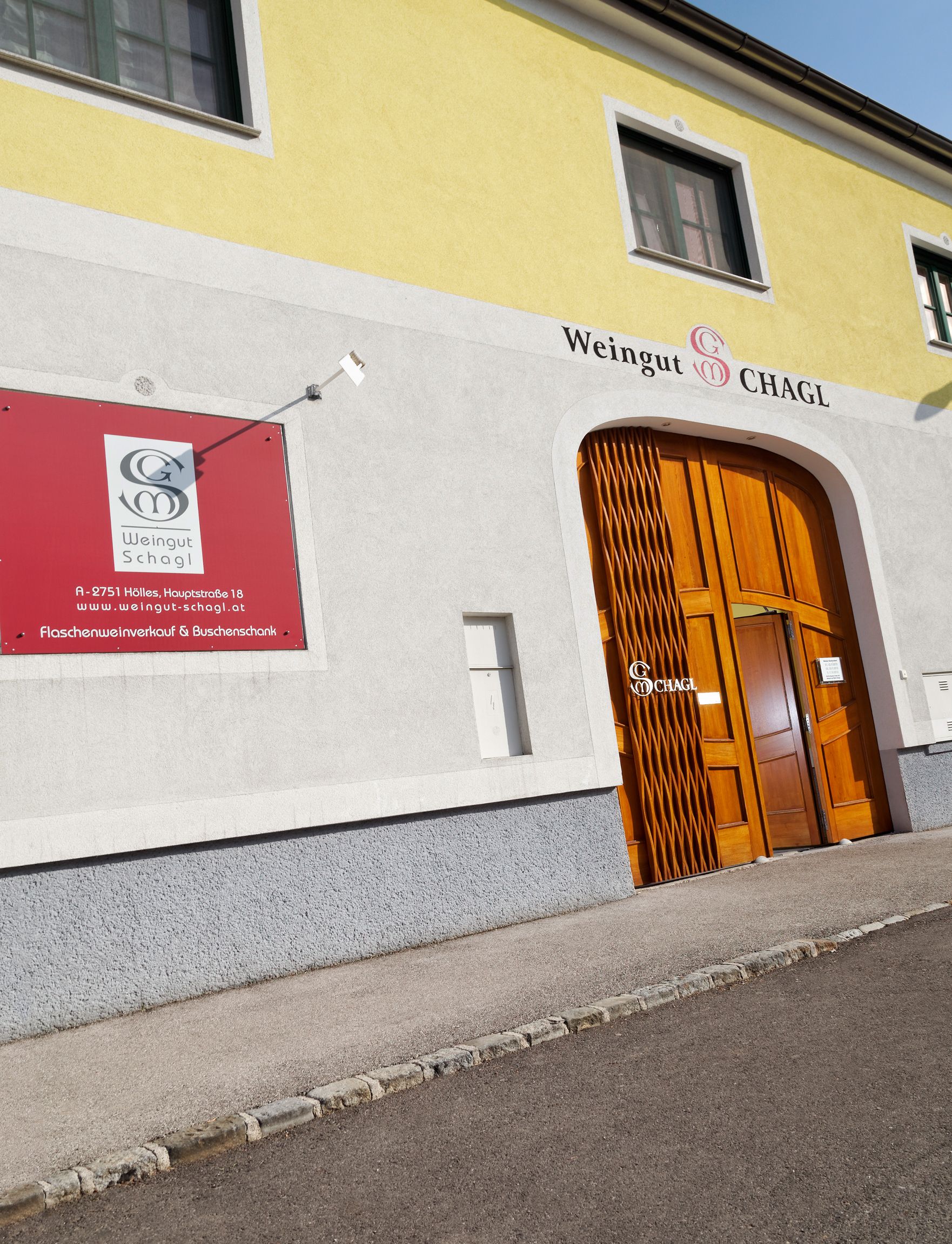 Entrance to the Schagl winery with yellow façade and wooden door.