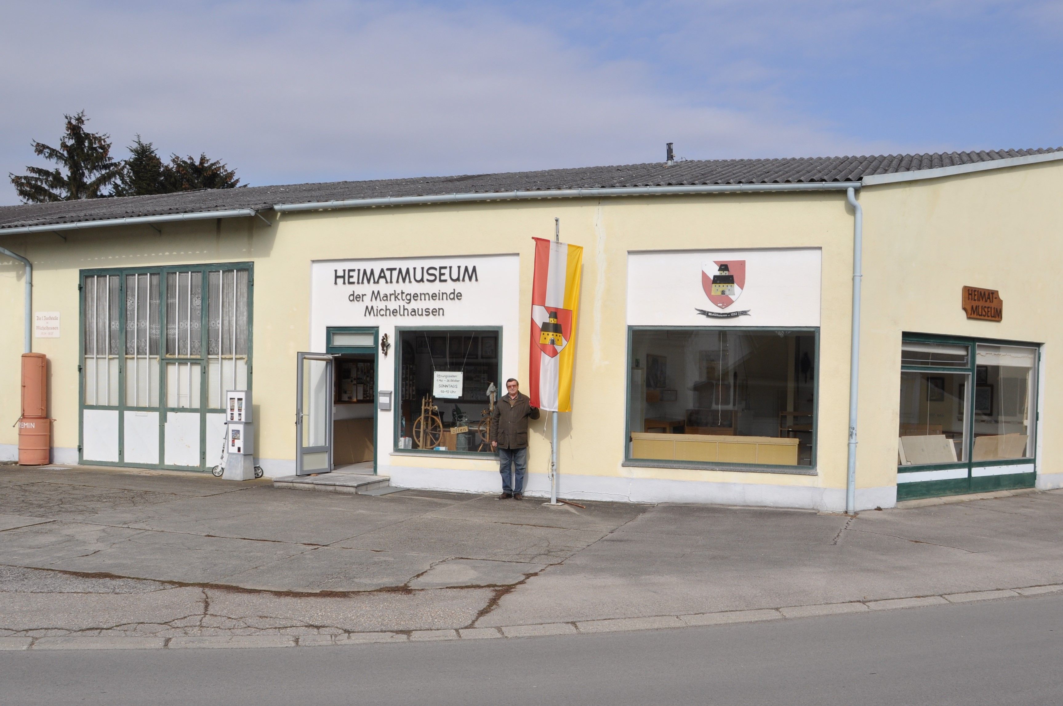 Exterior view of the Michelhausen local history museum with yellow building and flag.