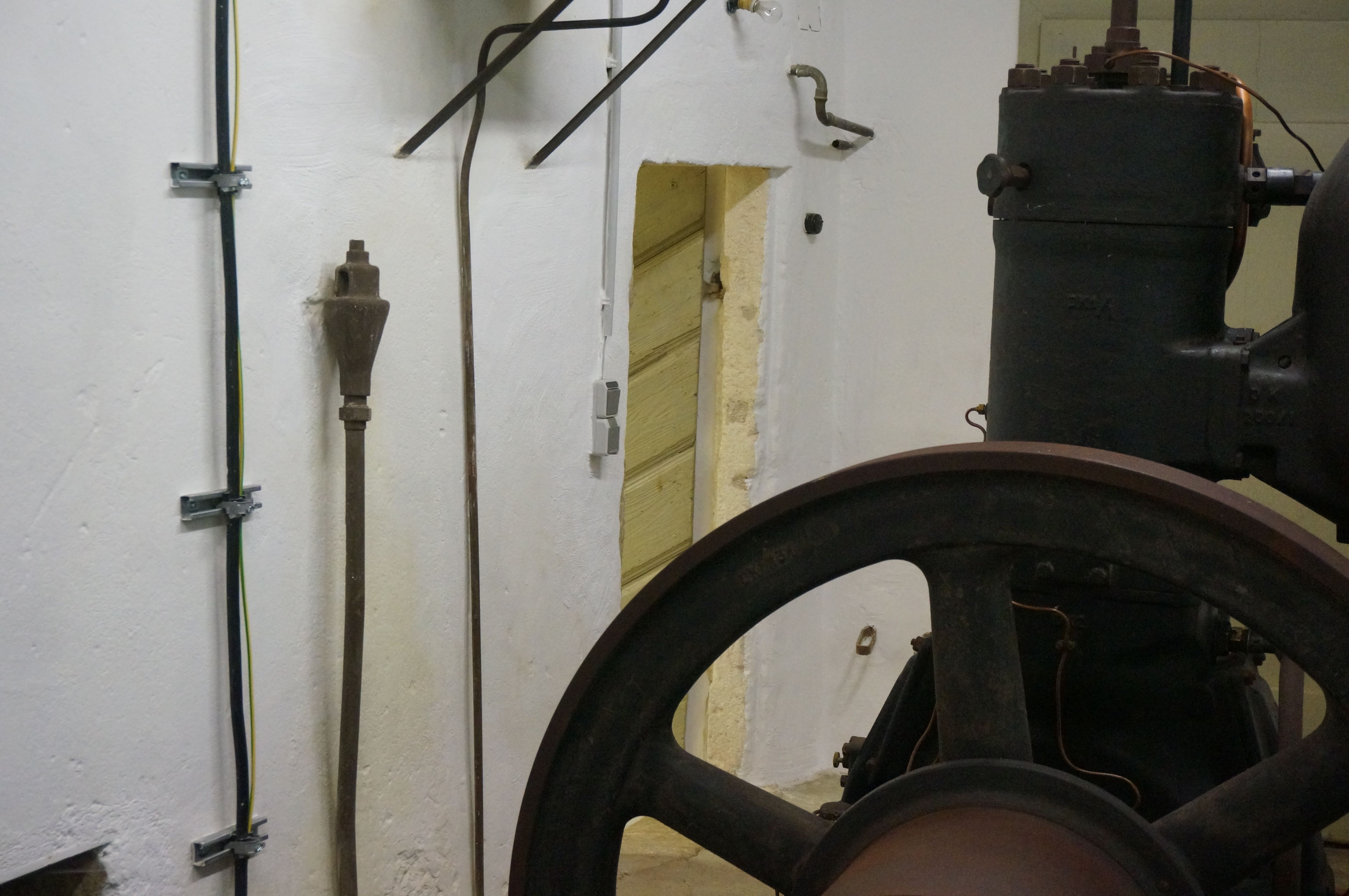 Old motor in a room with white walls and cables.