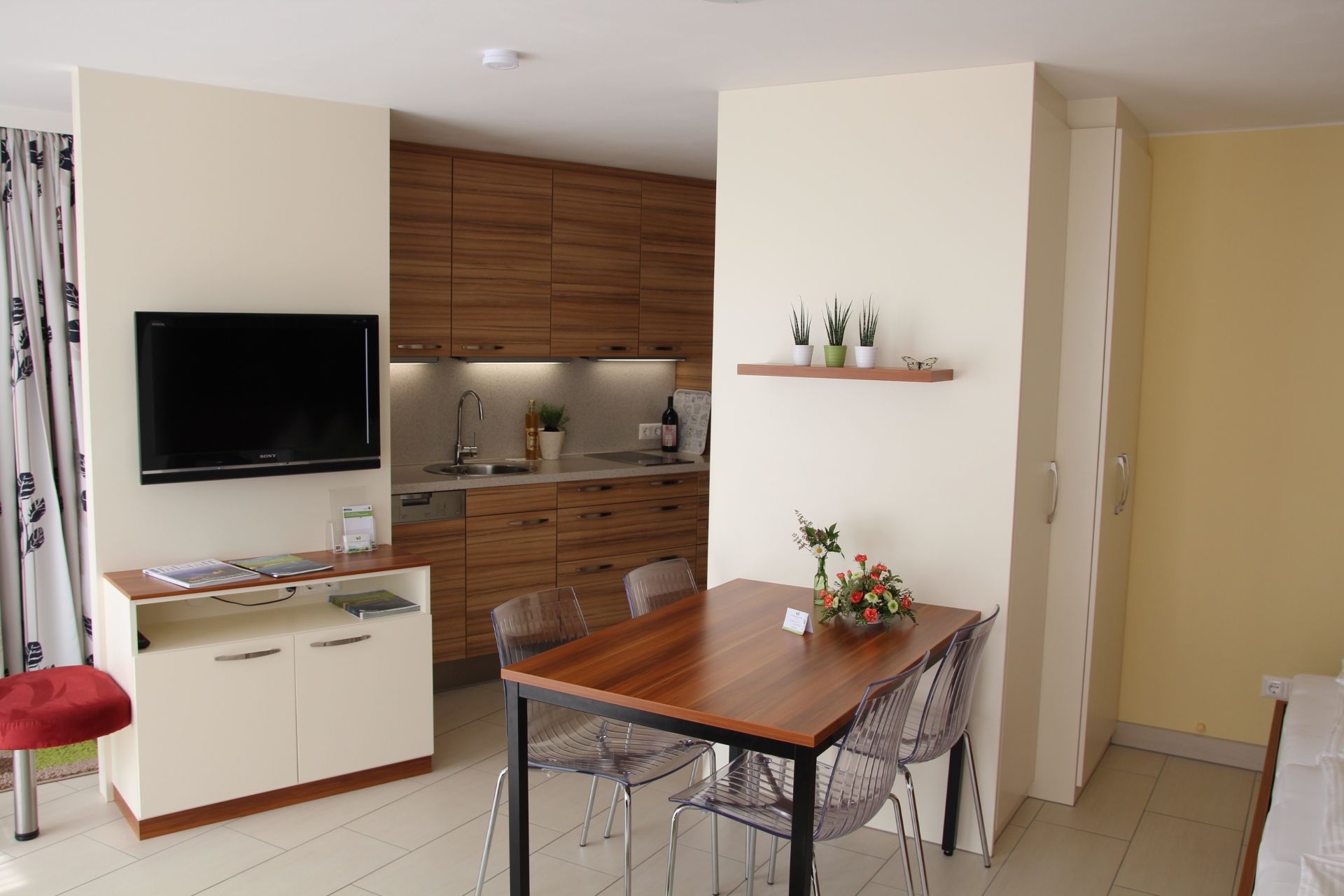 Modern garden apartment with kitchen, dining table and TV.