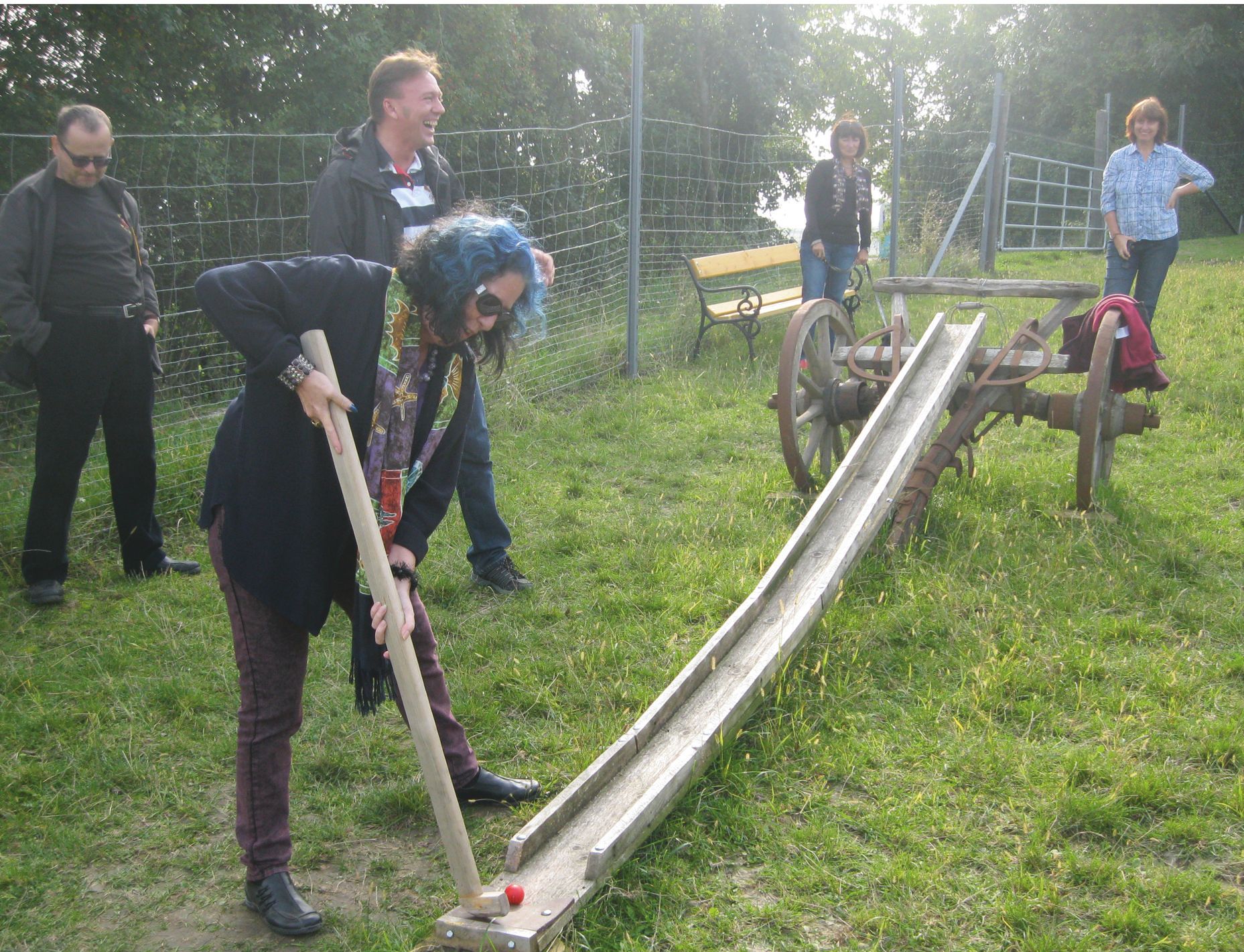 Person plays farmer's golf with a wooden club on a meadow.