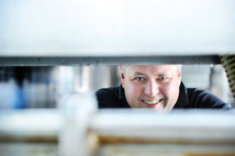 A man smiles through a narrow gap in an industrial setting.