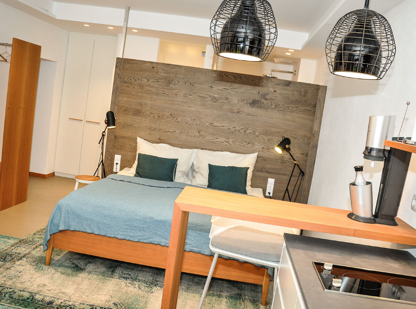 Modern studio apartment with bed, kitchen and stylish lighting.