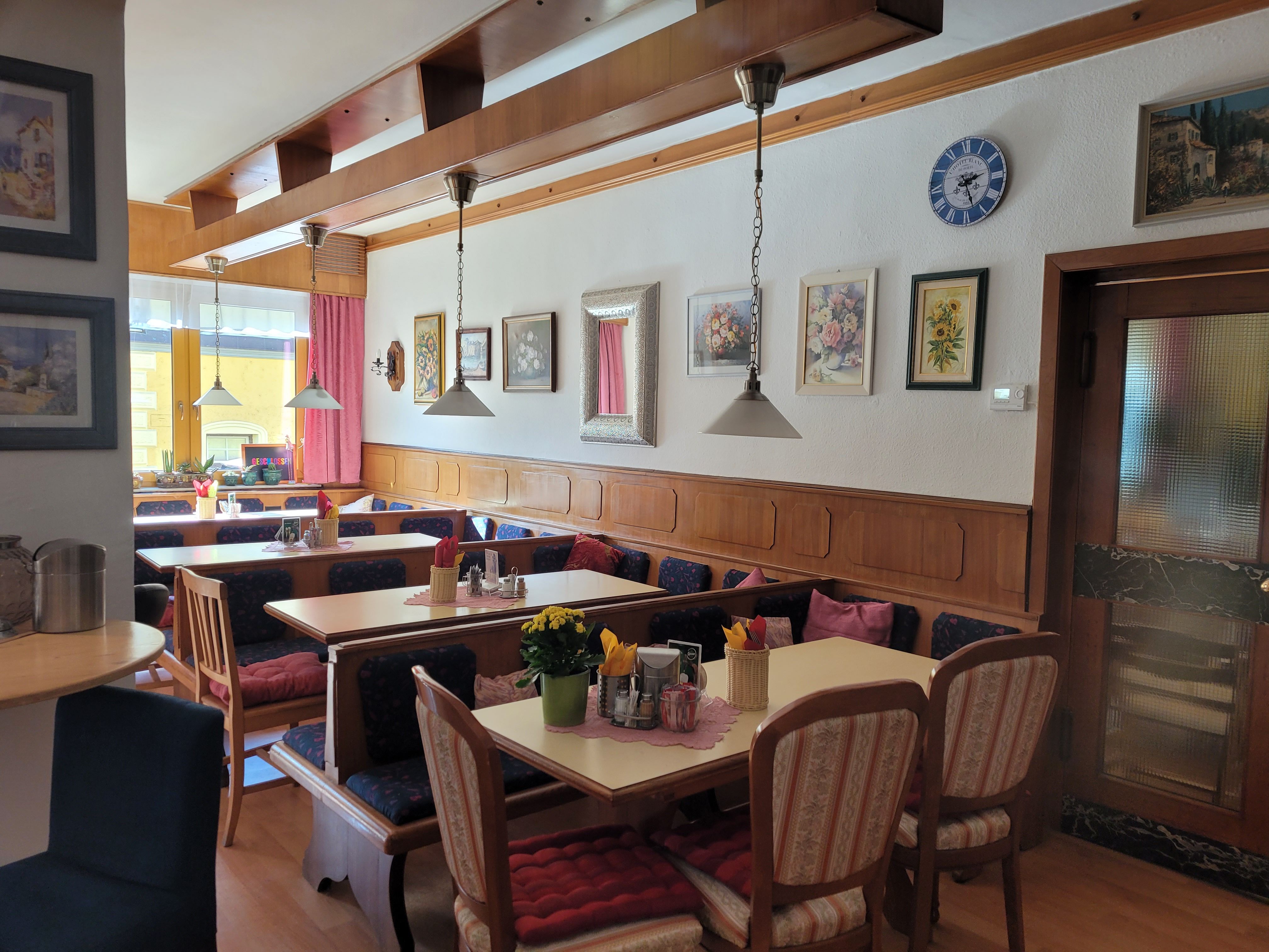 Cozy dining room with wooden furniture, decorative pictures on the wall and laid tables.