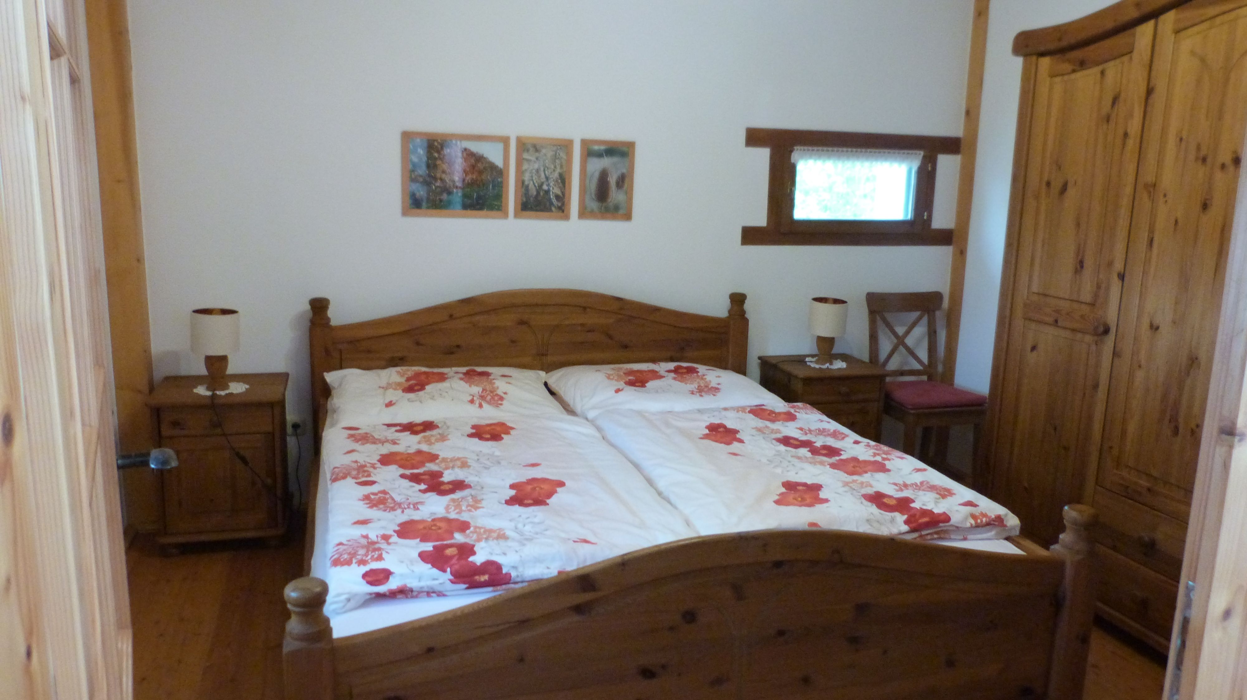 A cozy bedroom with wooden furniture and a double bed with floral bedding.