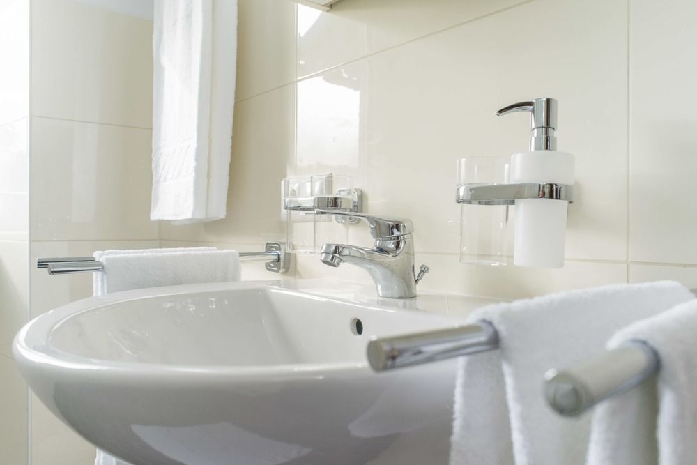 Modern bathroom with washbasin, towels and soap dispenser.