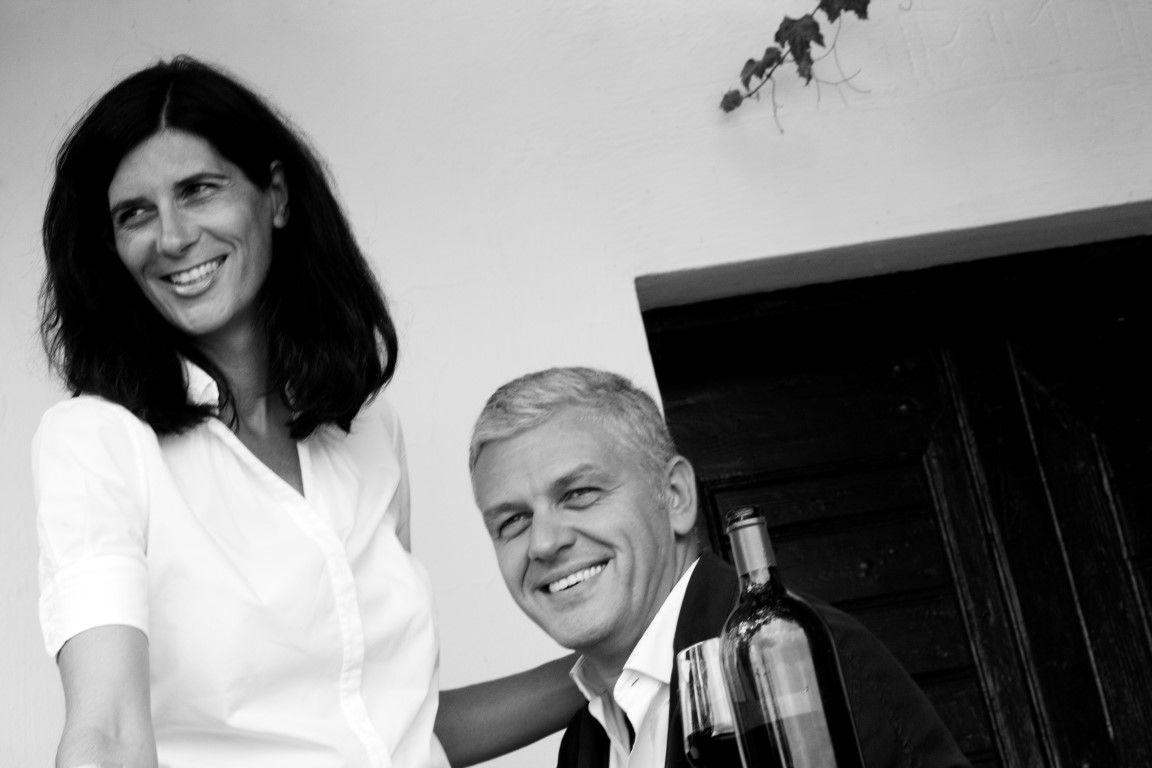 Black and white photo of a smiling couple with a bottle of wine.