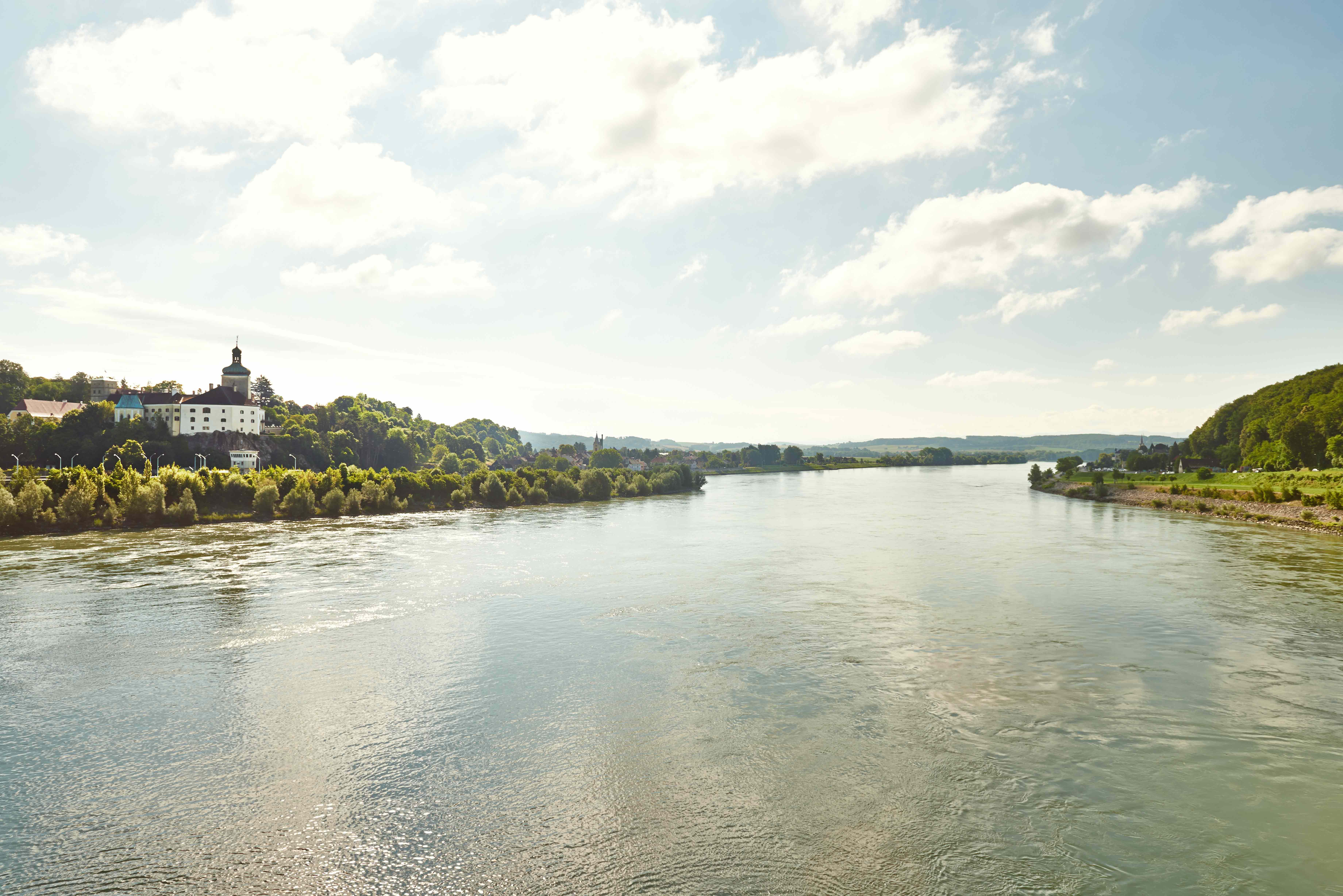 River landscape with buildings on the bank and cloudy sky.