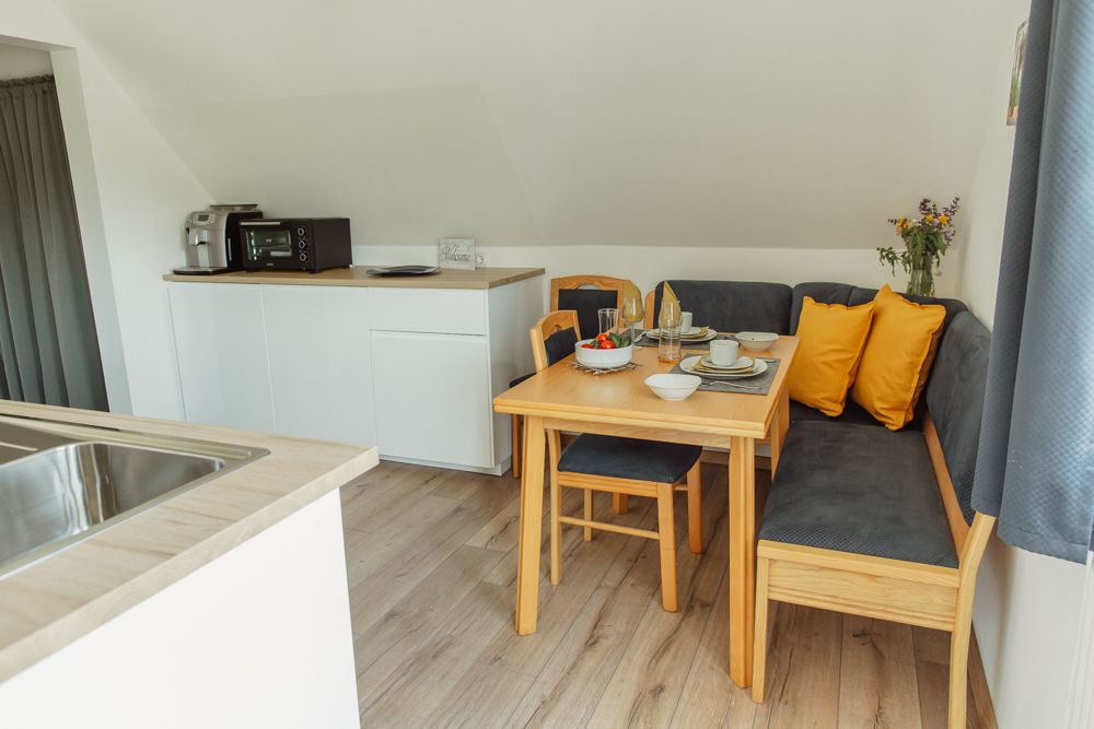Cozy dining area in a modern apartment with wooden table, corner bench and yellow cushions.