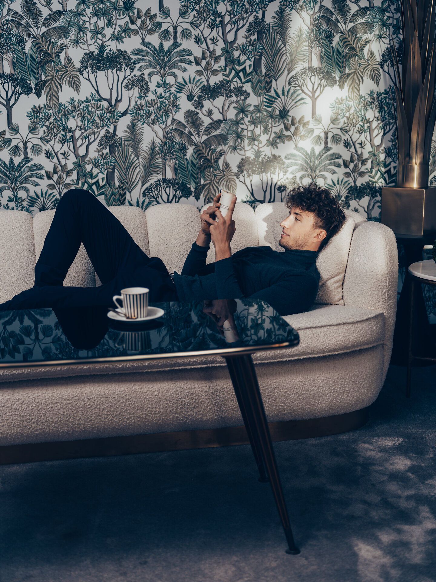 Inmitten der sanften Hügel der Wiener Alpen lädt eine gemütliche Couch zum Entspannen ein. Die üppige Pflanzenwelt im Hintergrund schafft eine harmonische Atmosphäre, während die sanften Lichtstrahlen den Raum erhellen. Hier kann man die Seele baumeln lassen und die Schönheit der Natur genießen.