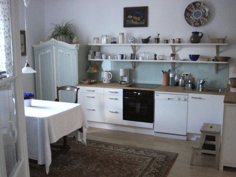 Cozy kitchen with dining table, cupboards and shelves.
