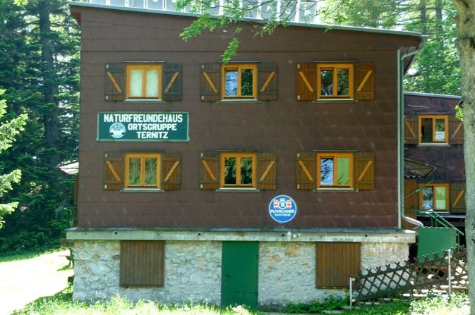 A three-storey building with wooden shutters and signs for Naturfreunde Ternitz.