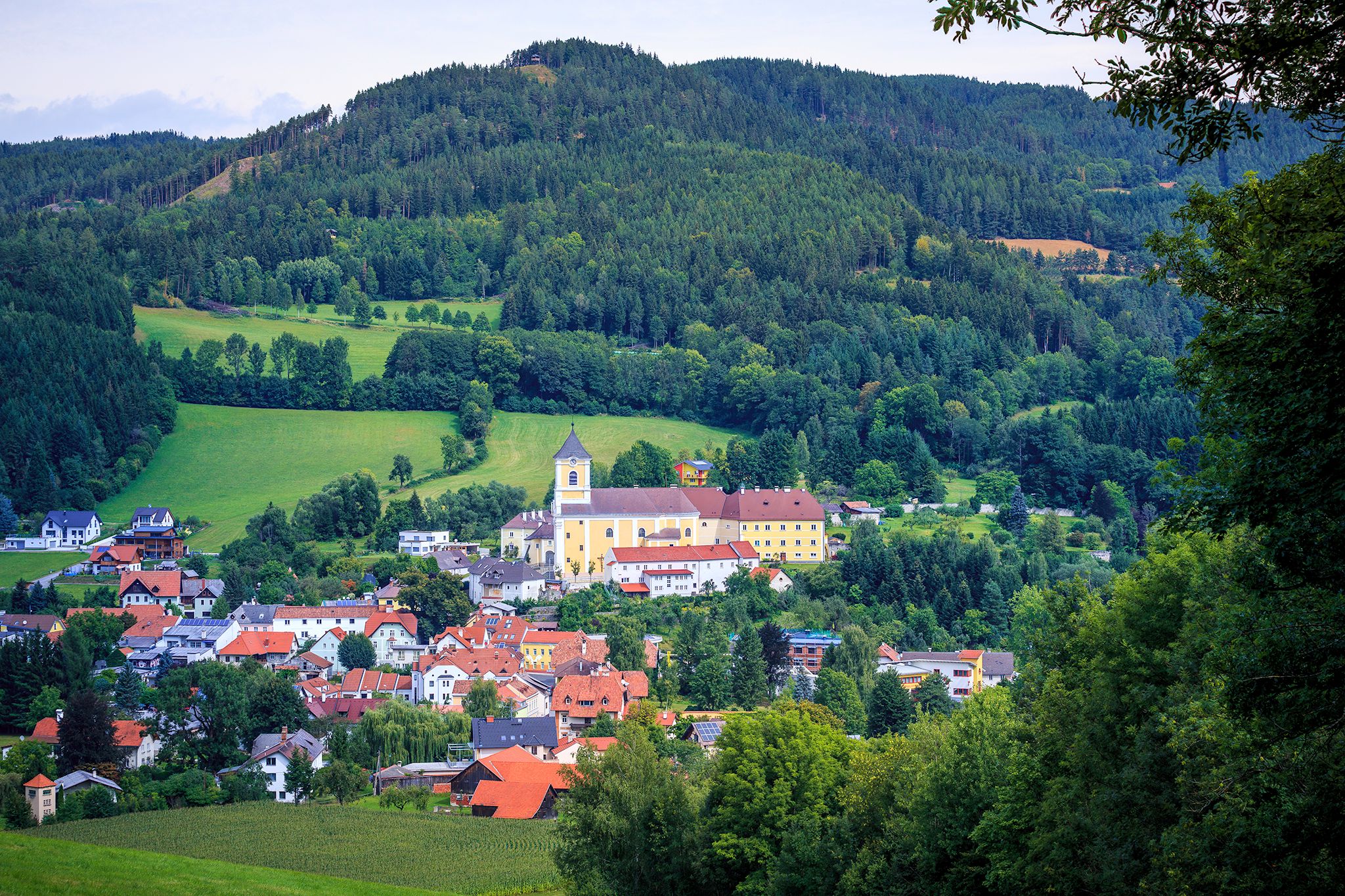 Landscape with church and monastery in a village surrounded by forests and hills.