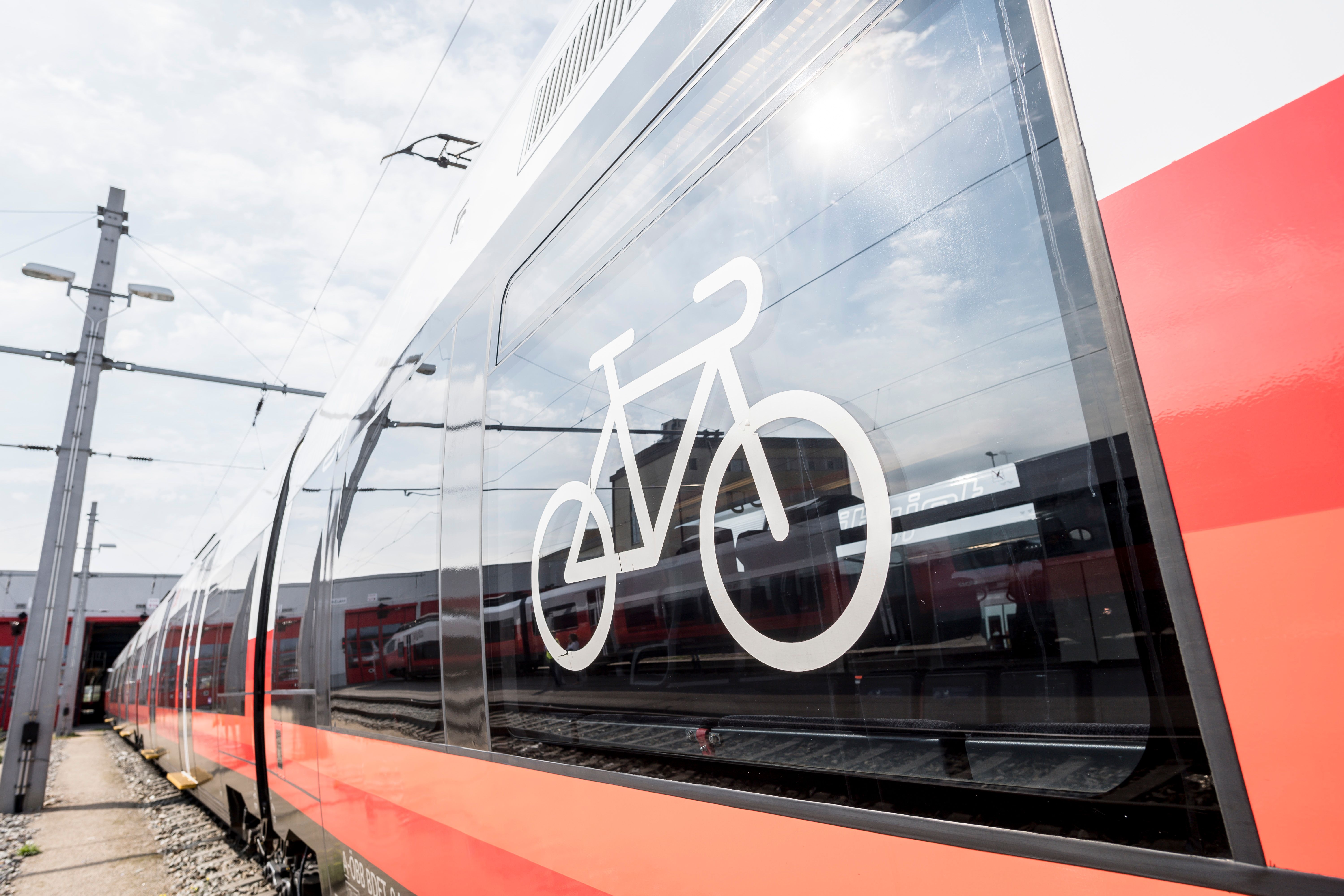 Close-up of a red train with a bicycle symbol on the window indicating that bicycles can be carried.