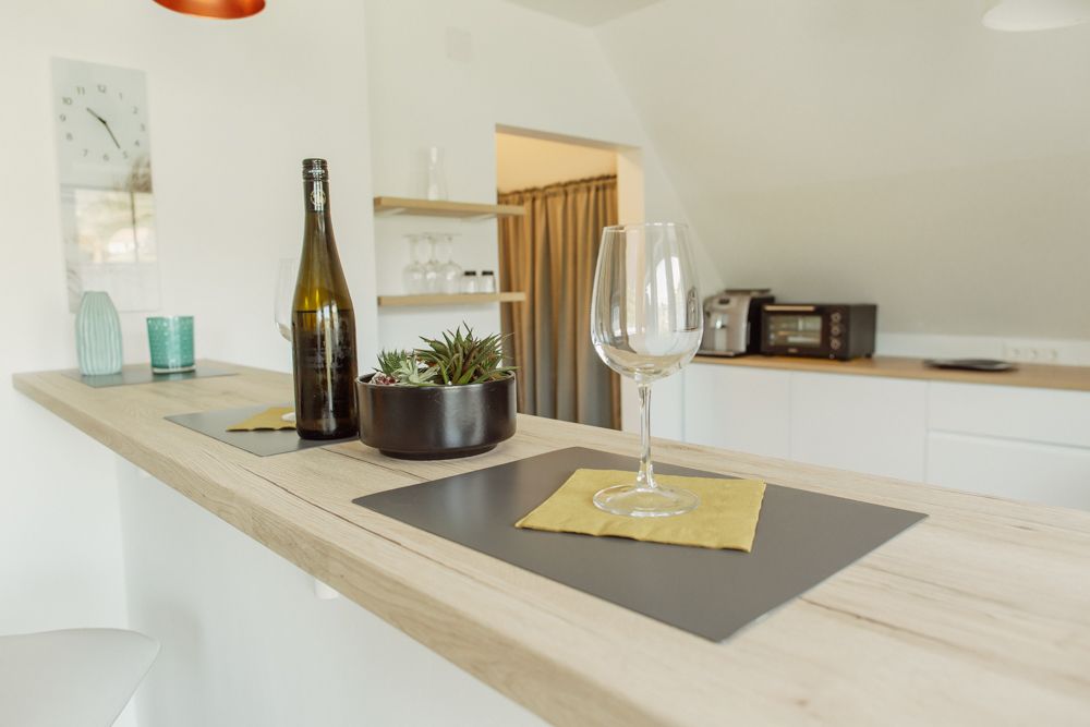 Modern kitchen with bar counter, wine glass and bottle.