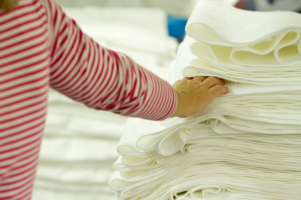A hand touches a pile of white towels.