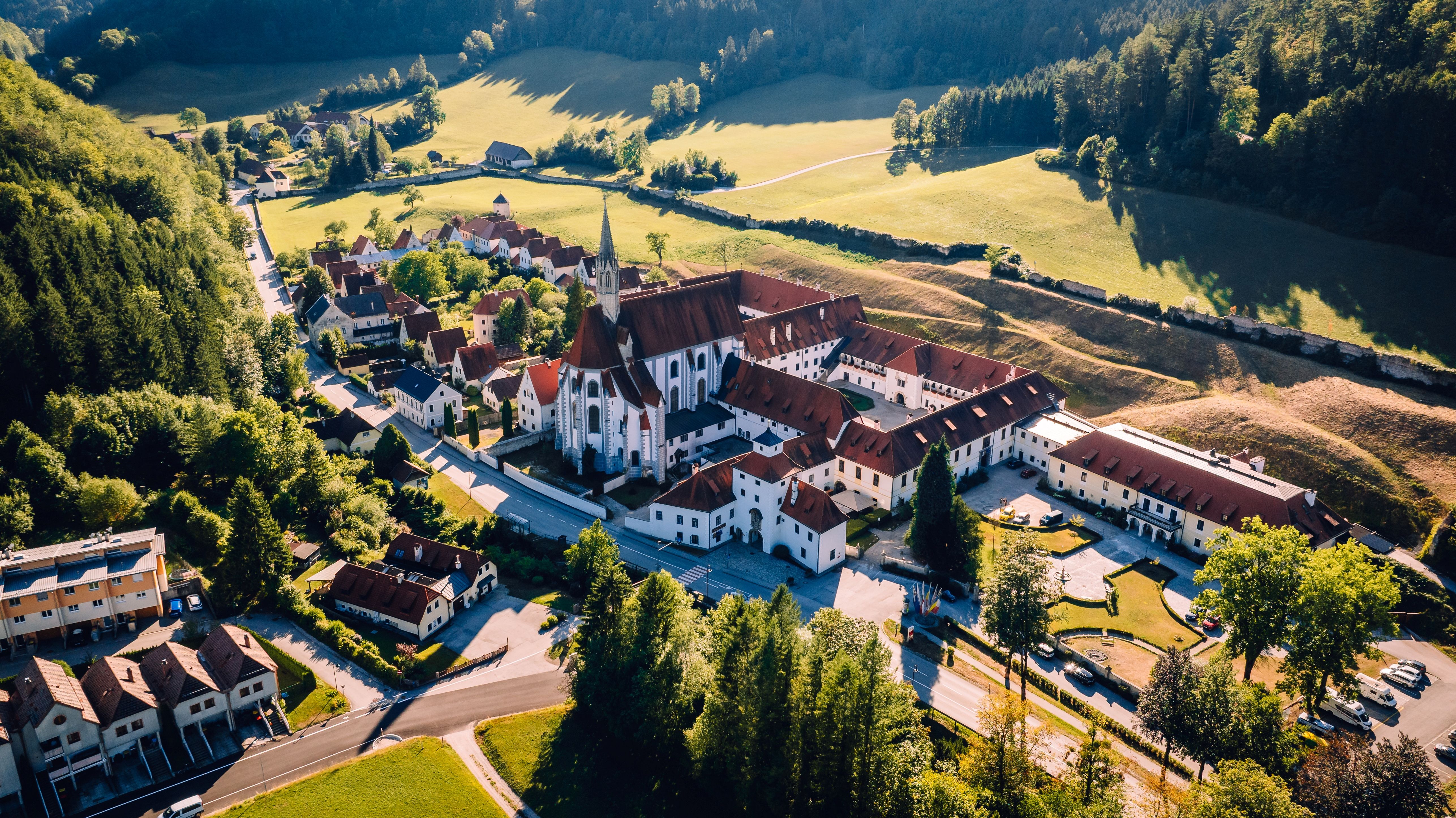 Aerial view of the Gaming Charterhouse and the surrounding meadows in a valley.