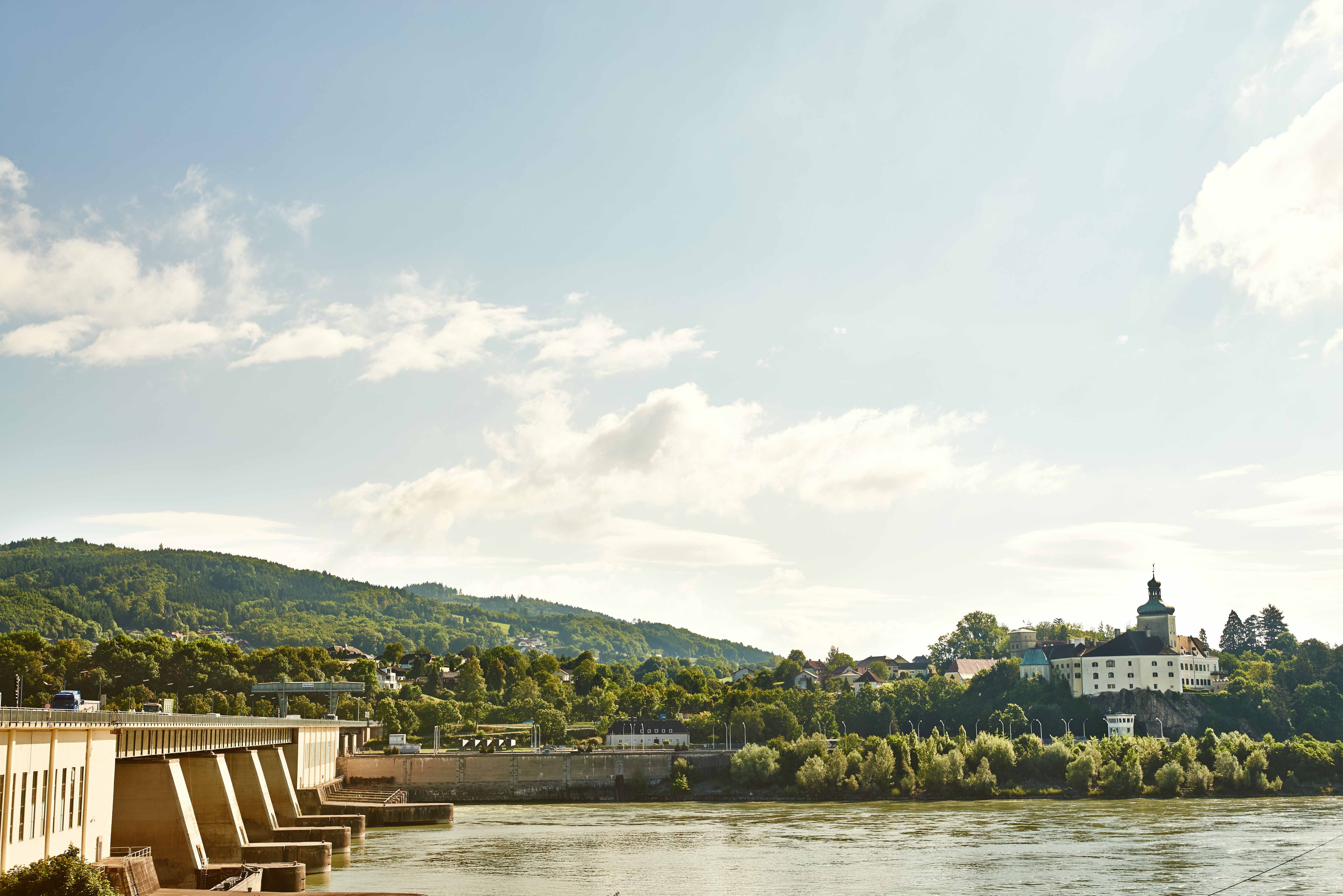Ybbs-Persenbeug power station on a sunny day with the river and wooded hills in the background.