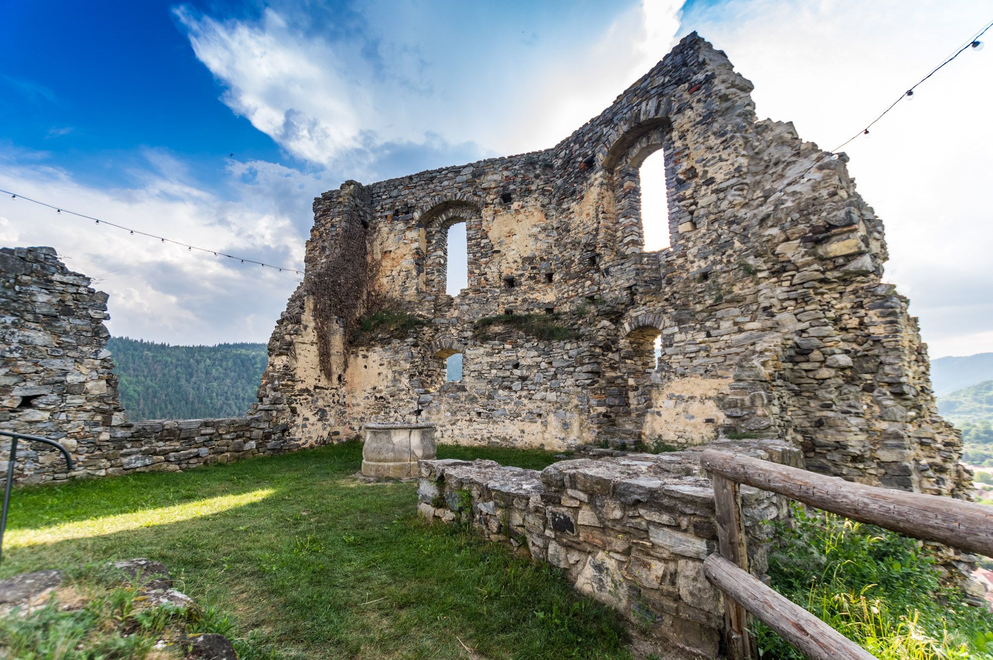 Ruins of Senftenberg Castle with stone walls and windows, surrounded by a green landscape and blue sky.