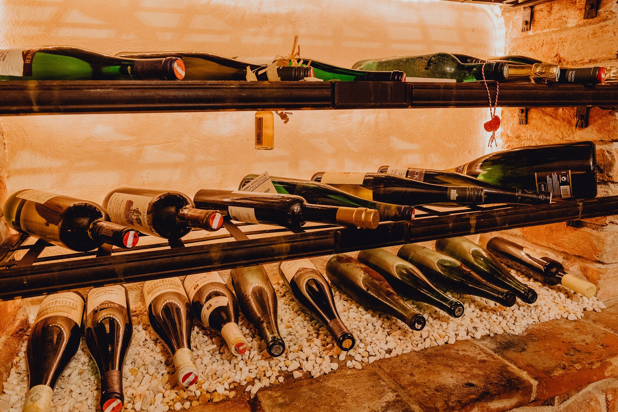 Wine bottles on a shelf on white stones.