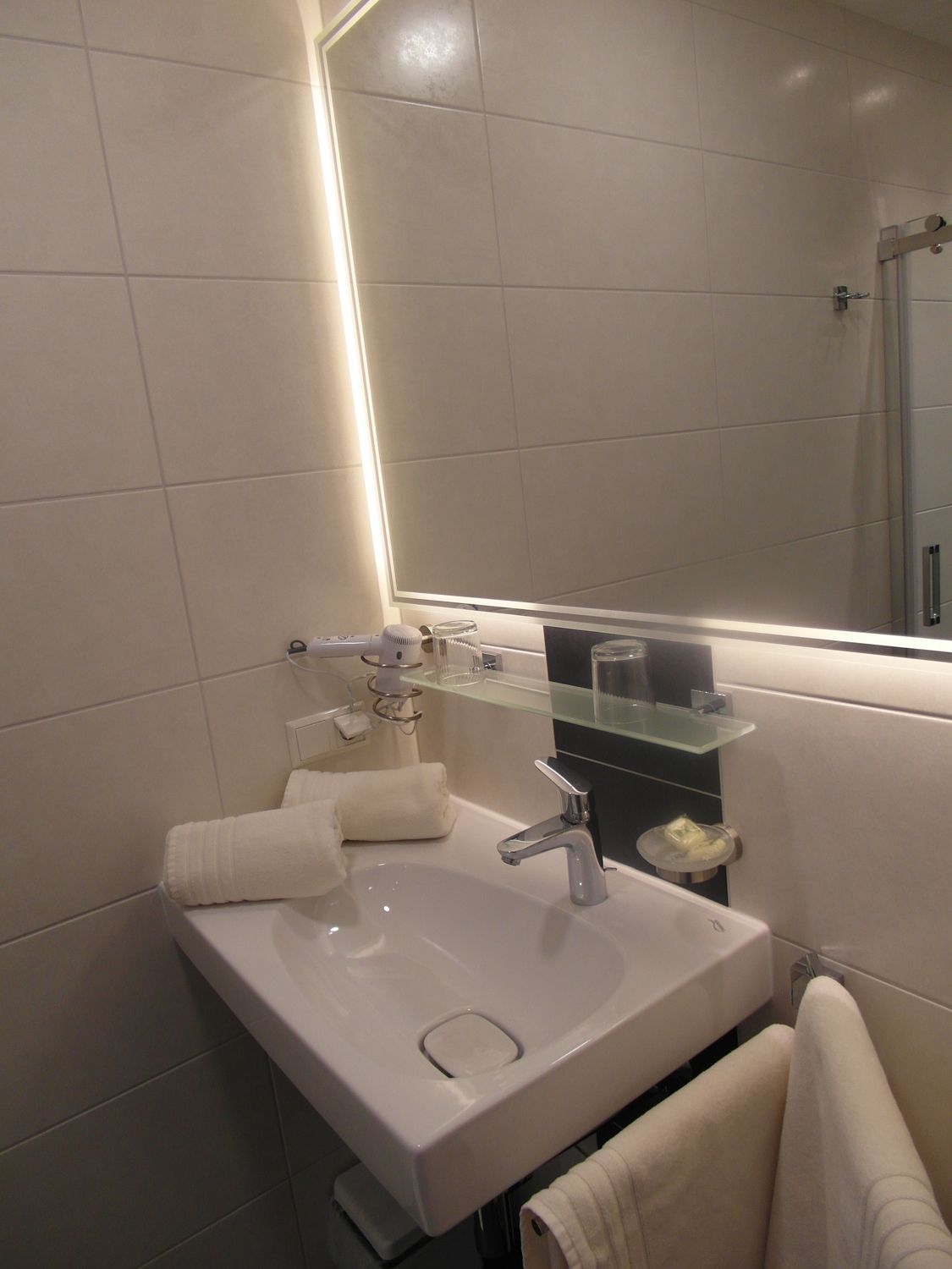 Modern bathroom with washbasin, mirror and towels.