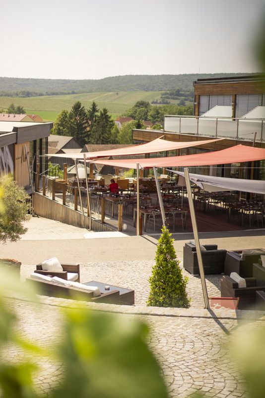 Terrace with awnings and seating, surrounded by green countryside.