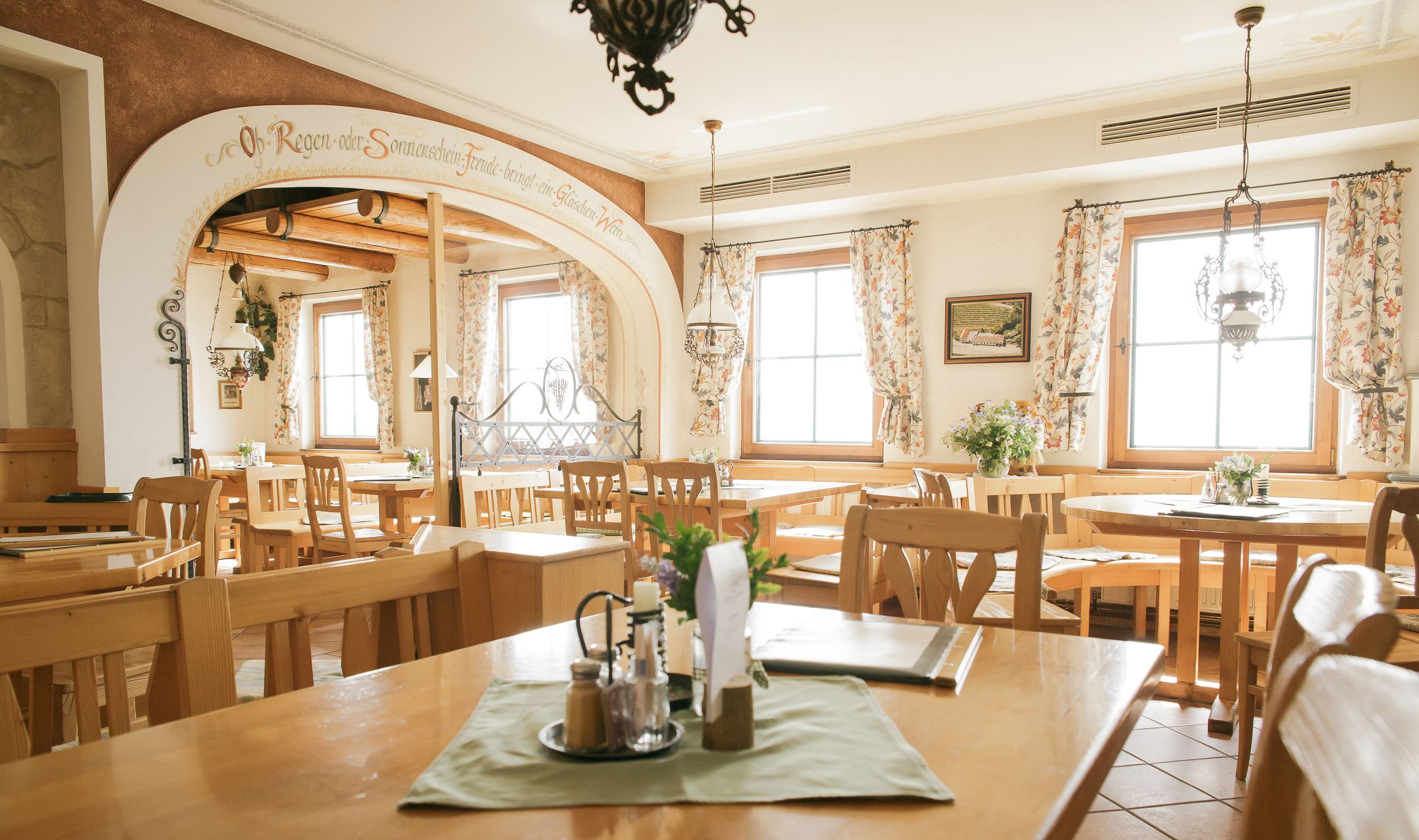 Interior view of a cozy restaurant with wooden furniture and floral curtains.