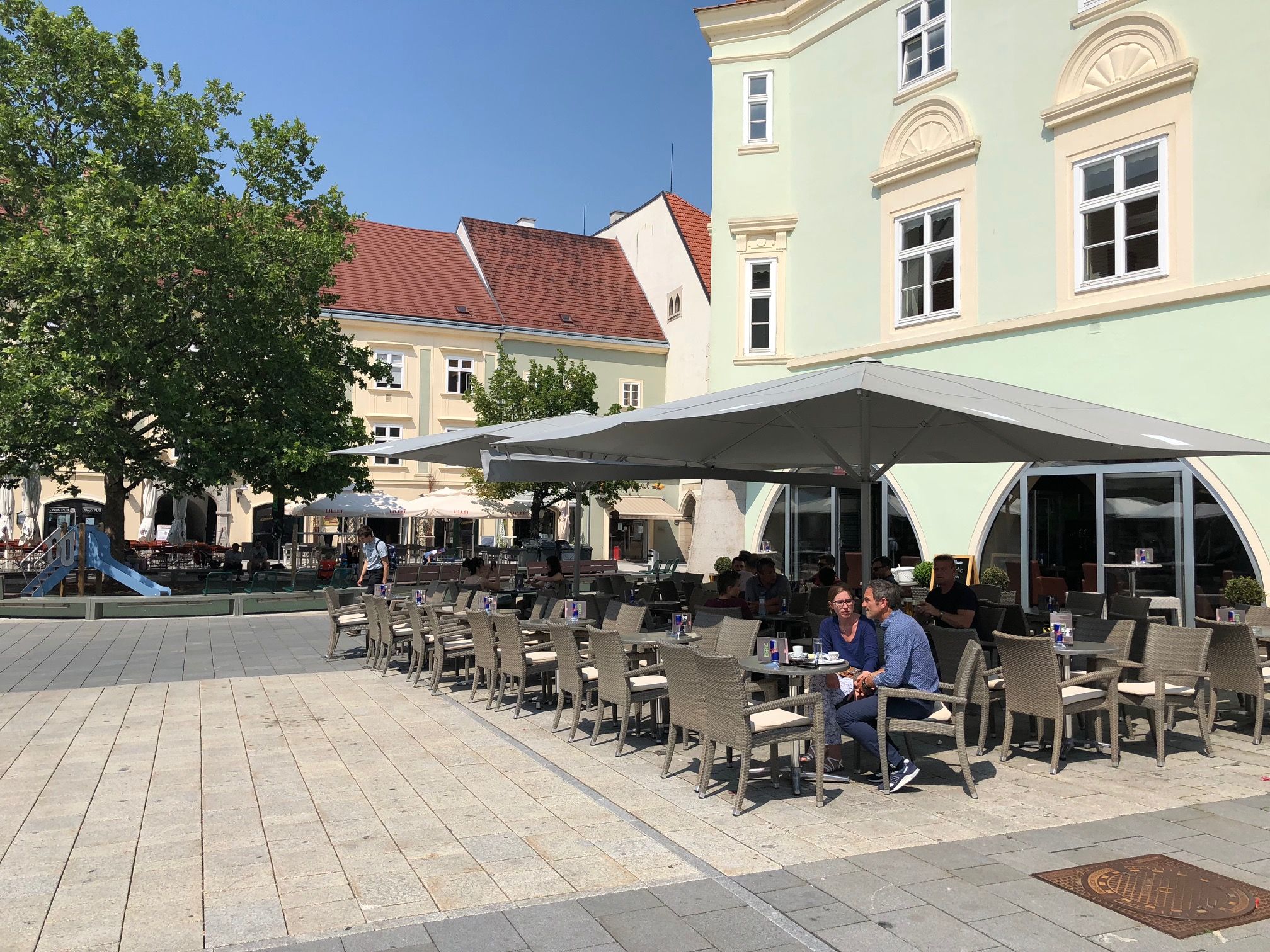 A pavement garden in front of the Eterno with parasols and seating on a paved square.