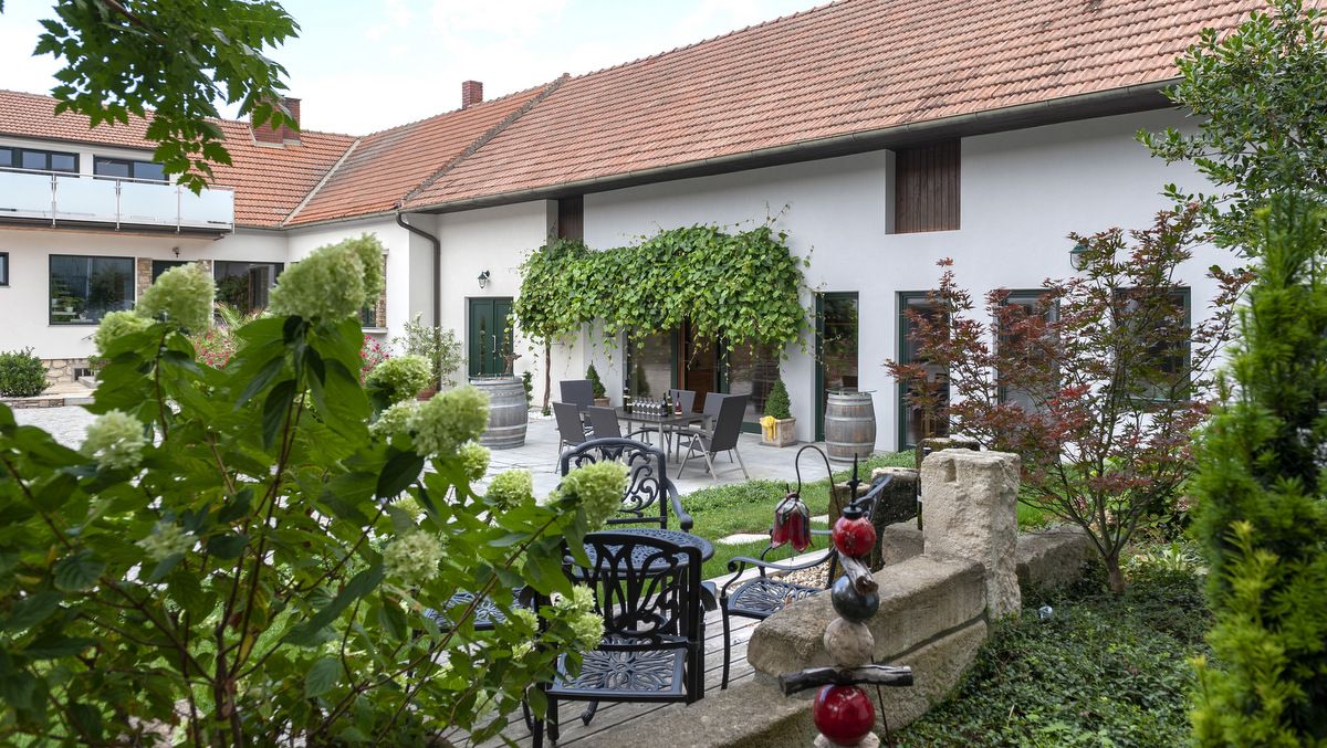 A cozy courtyard of a winery with plants, garden furniture and wine barrels.