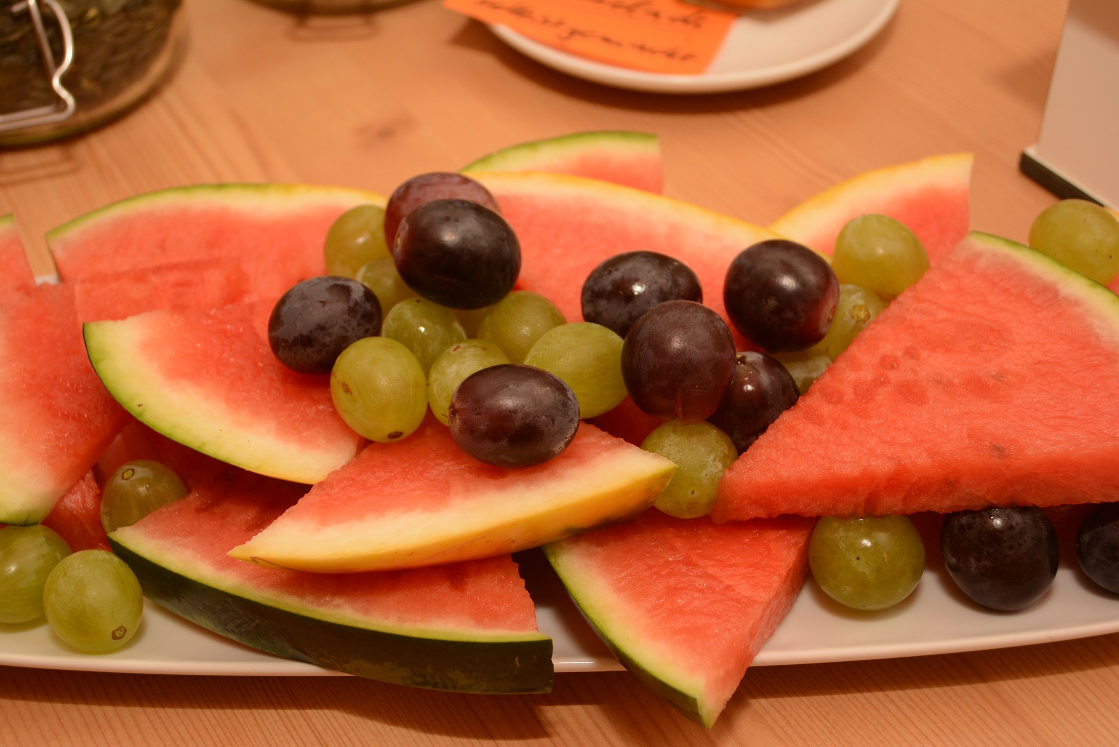 A plate with pieces of watermelon and grapes.