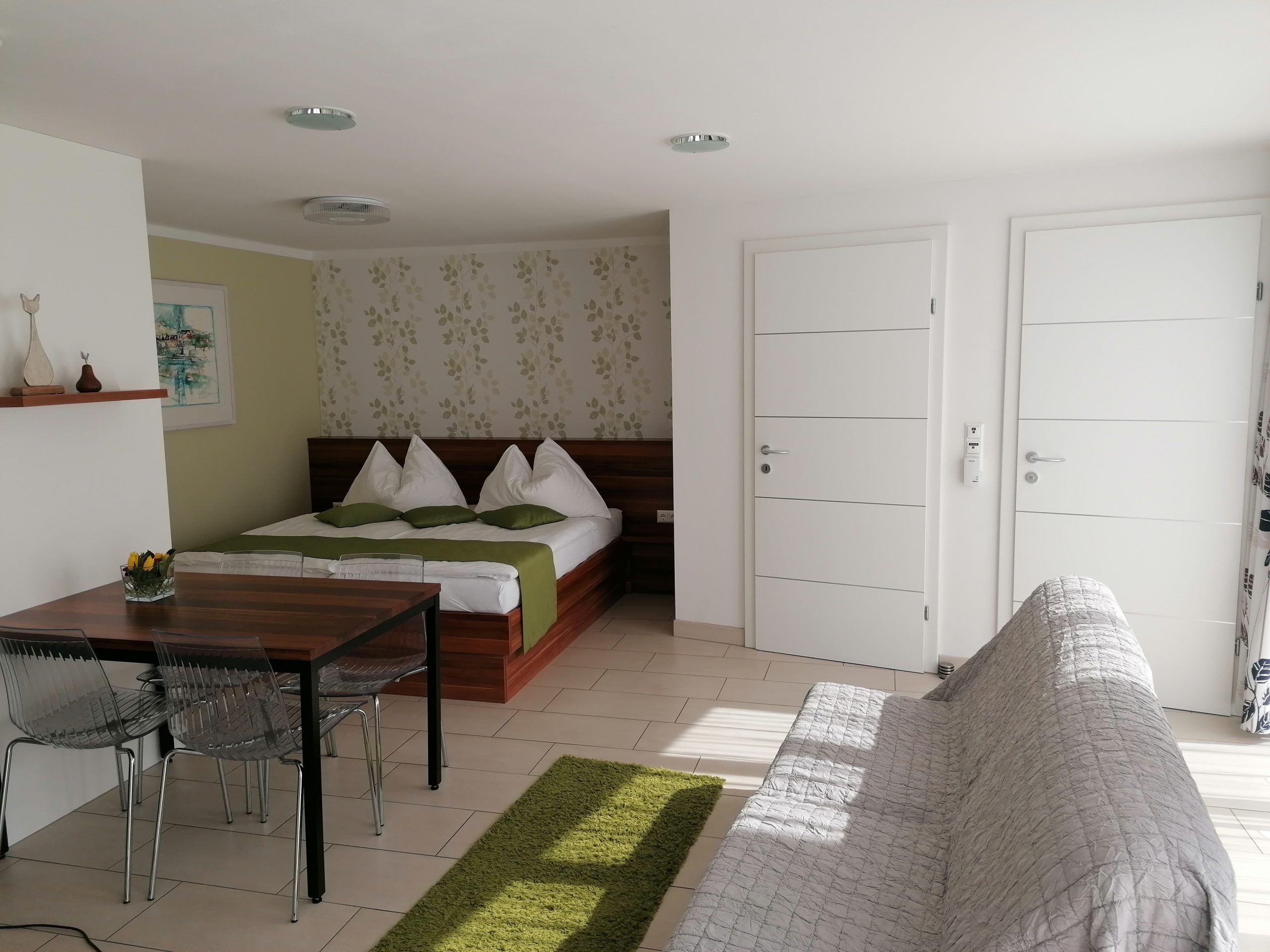 Room with double bed and two white entrance doors