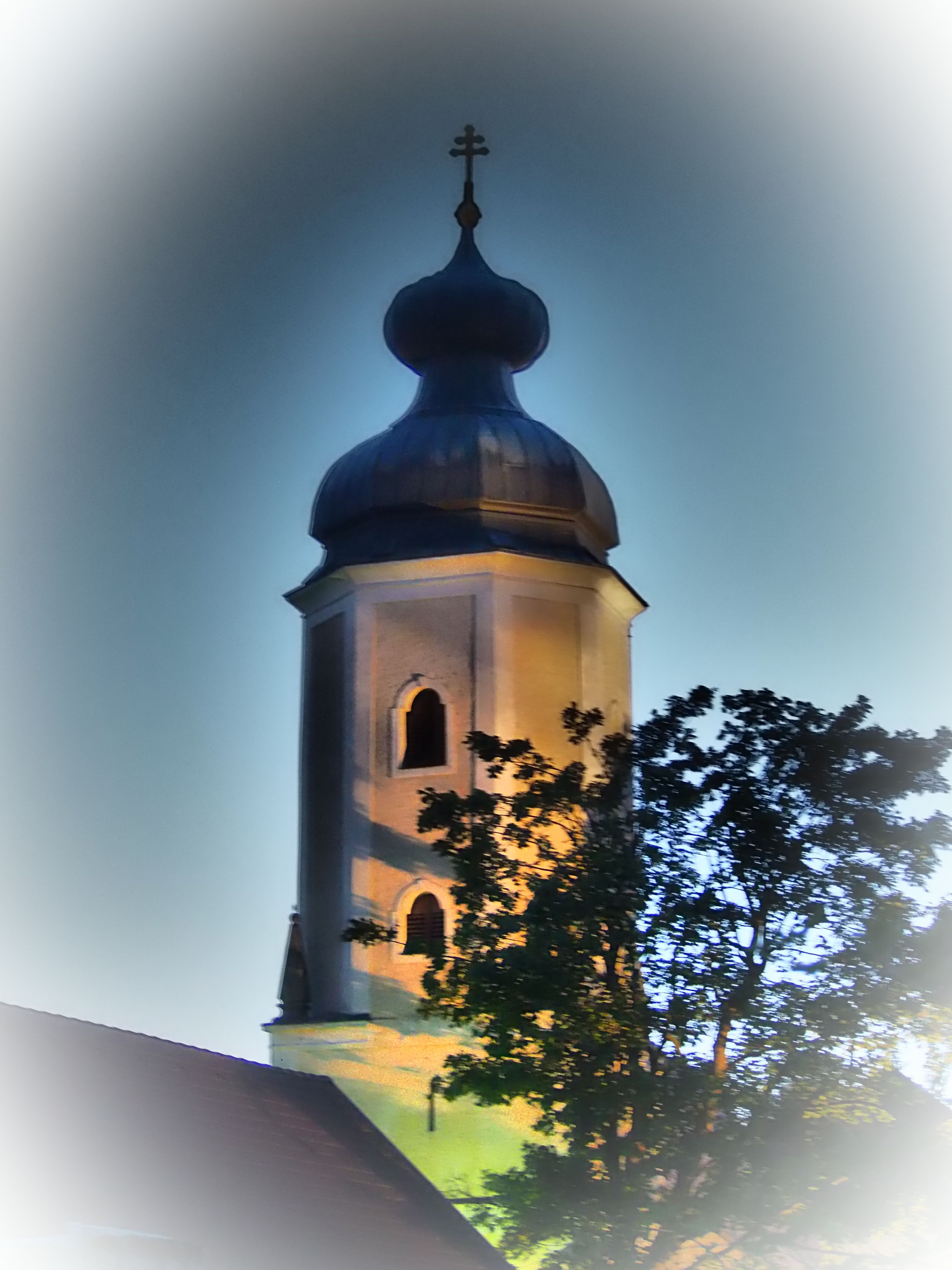 Illuminated church tower of the Sallingberg parish church at dusk.