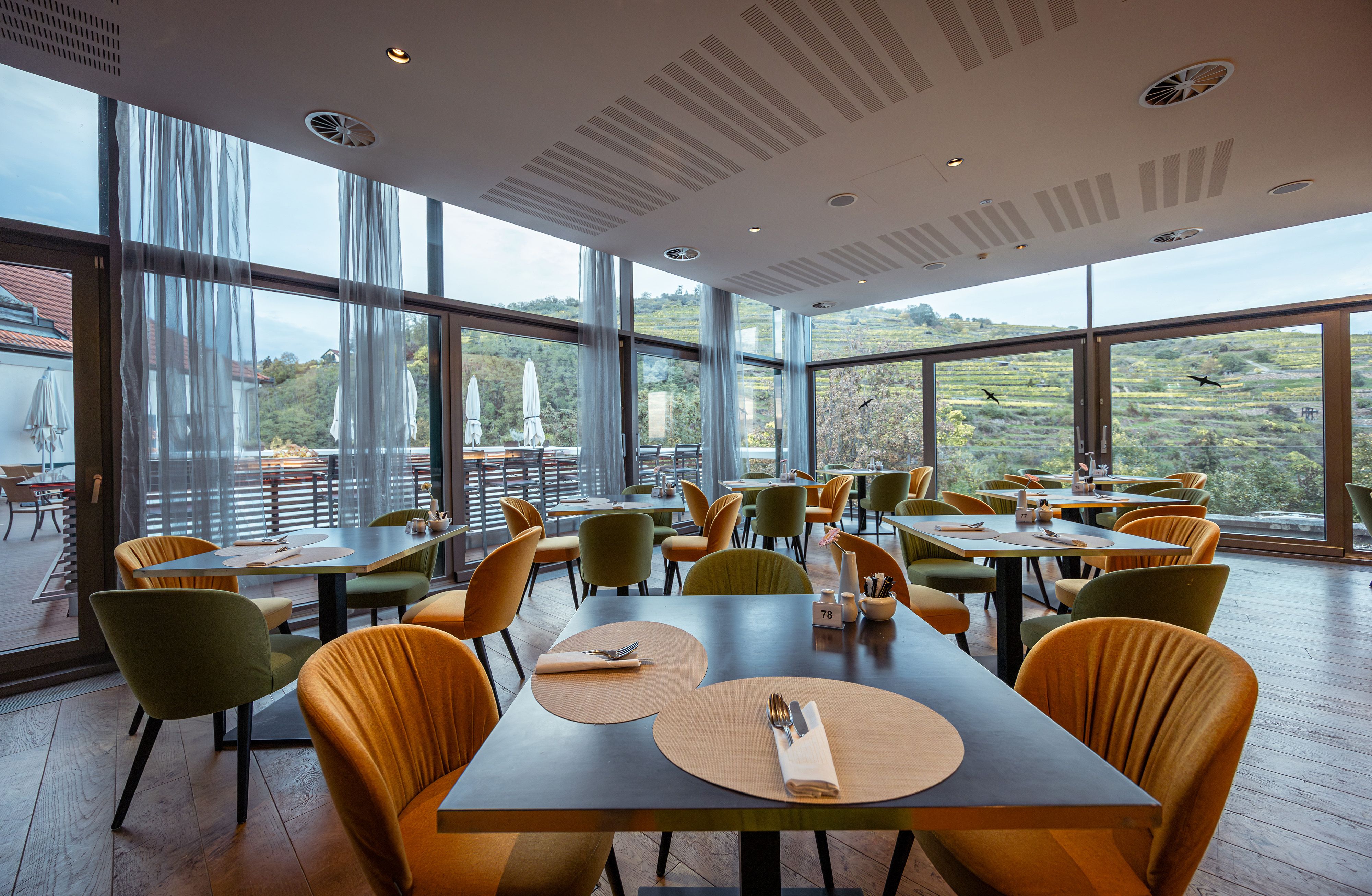 Interior view of the modern restaurant with large windows and a view of the vineyards.