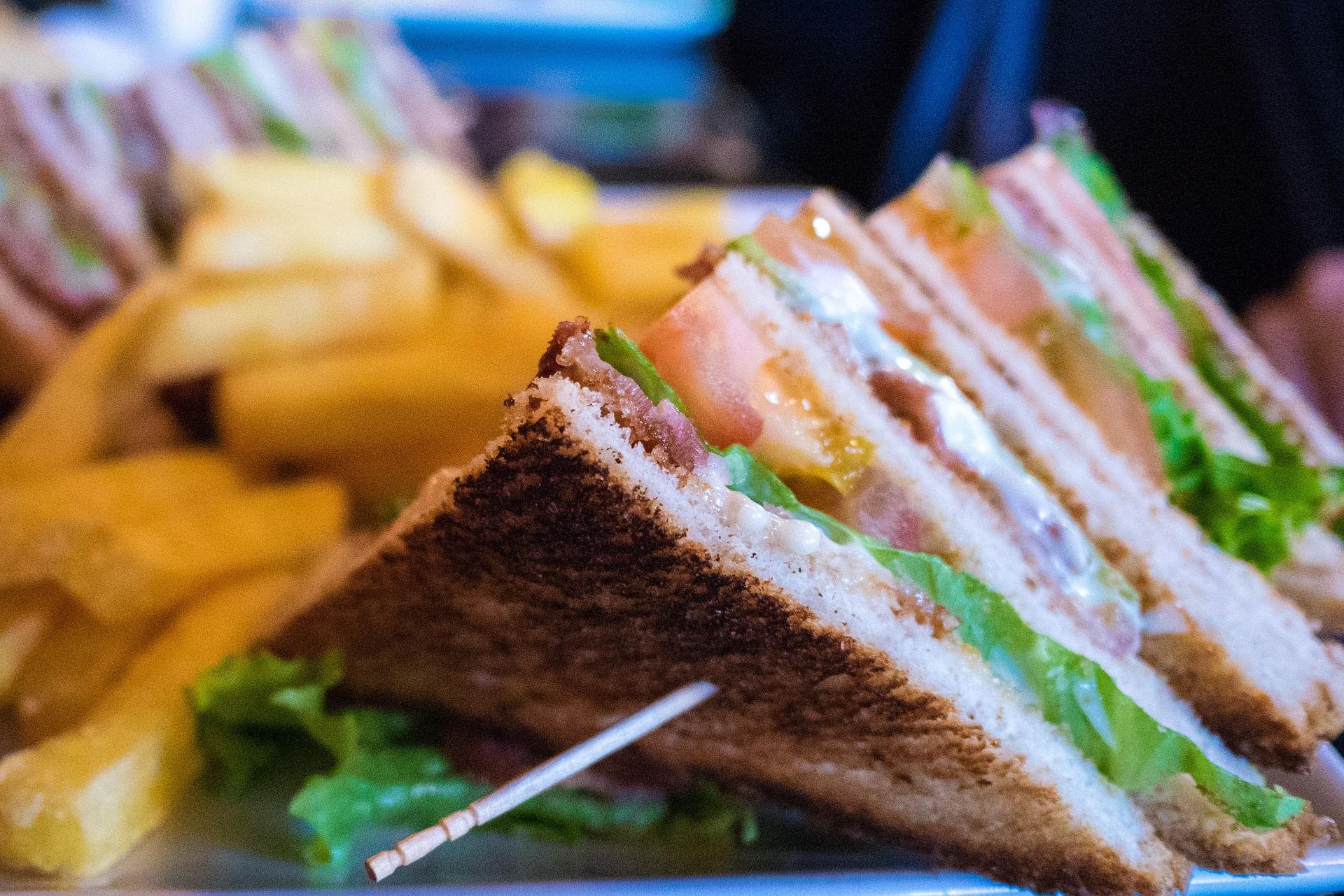Close-up of club sandwiches with French fries in the background.