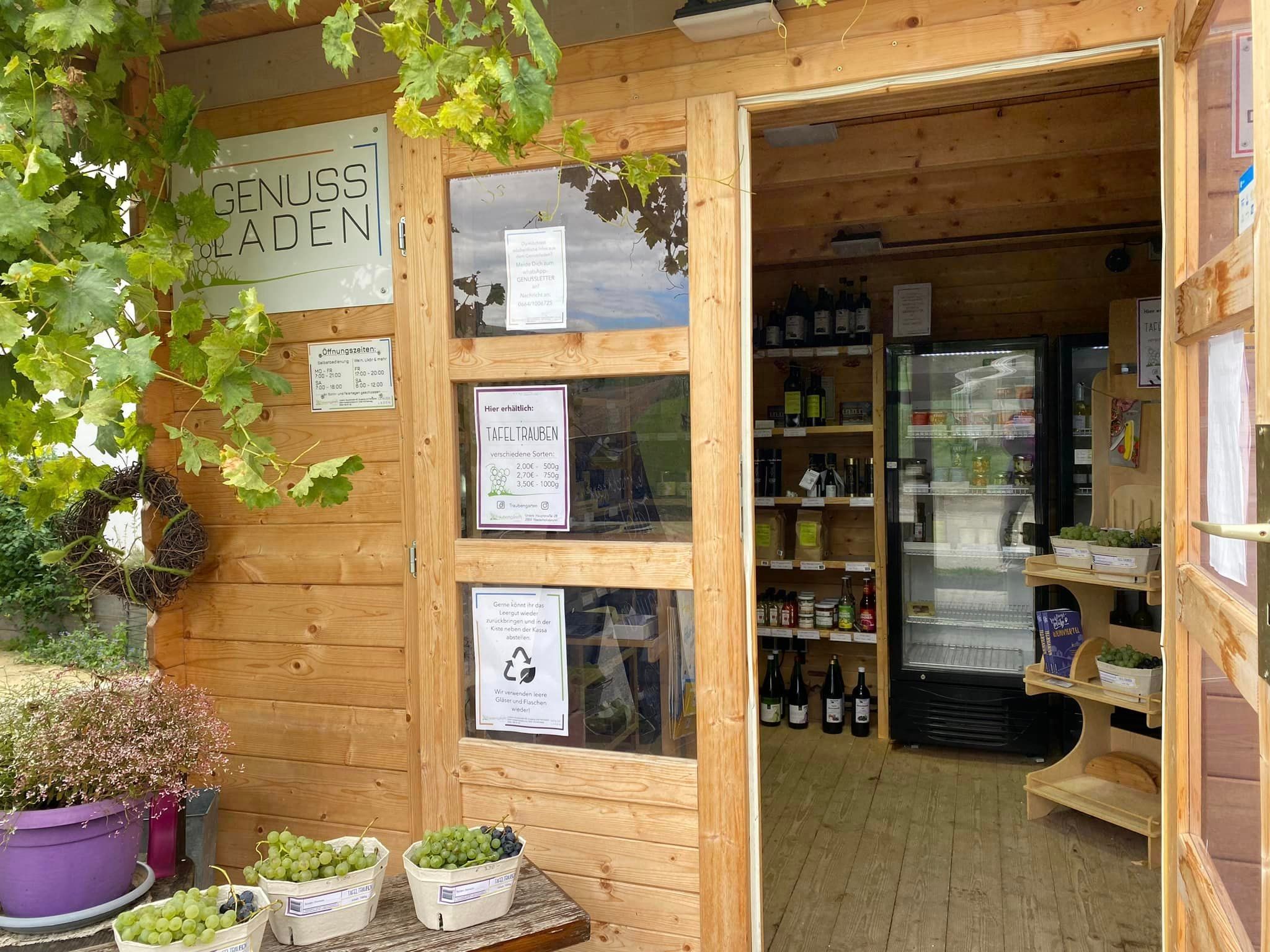 A small wooden store with grapes and drinks inside.