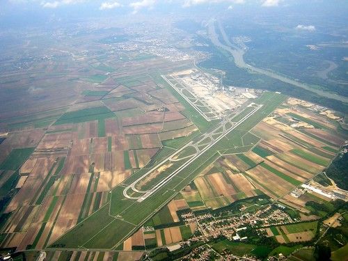 Aerial view of an airport with surrounding fields and a river in the background.