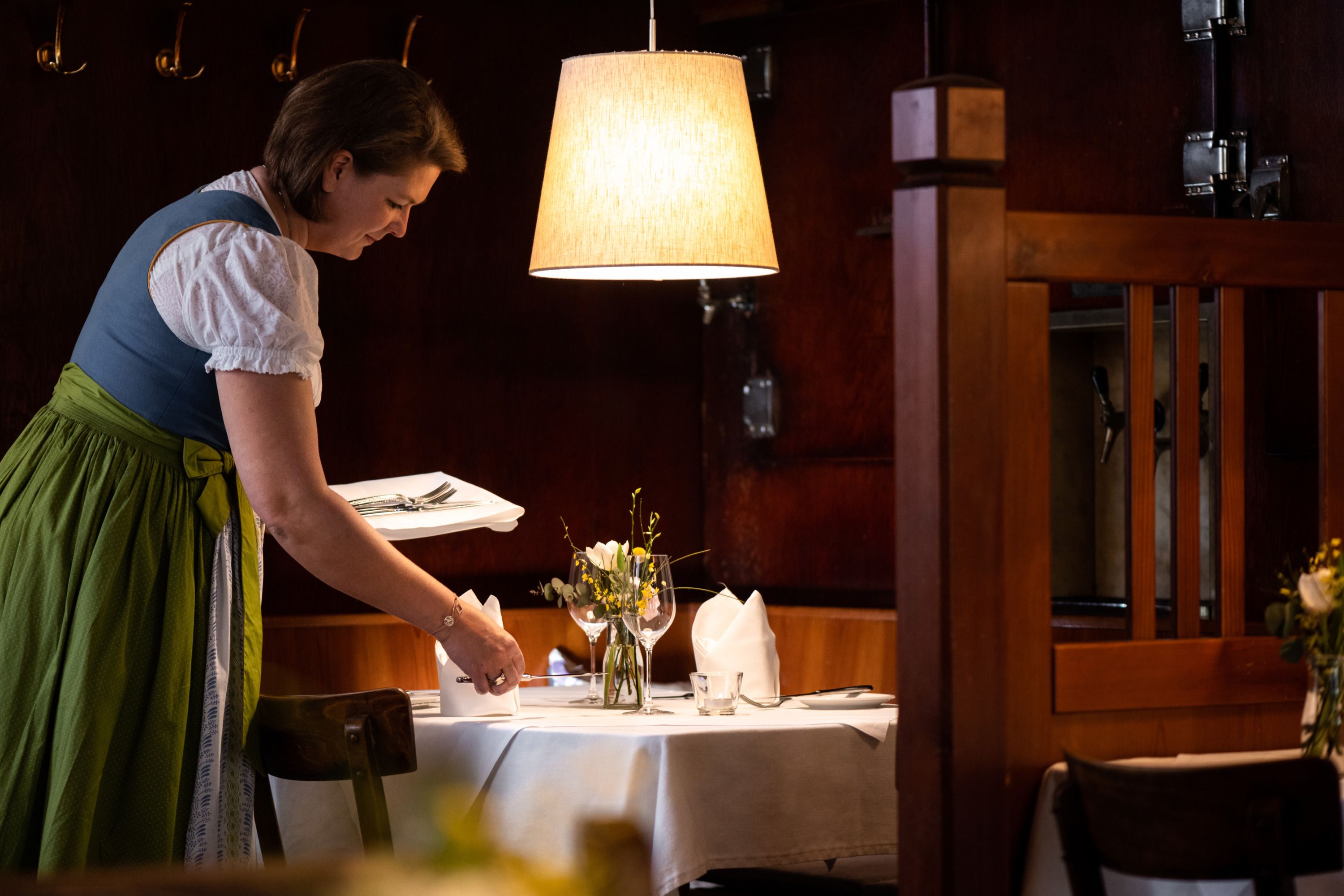 Waitress in traditional costume sets the table in a cozy restaurant.