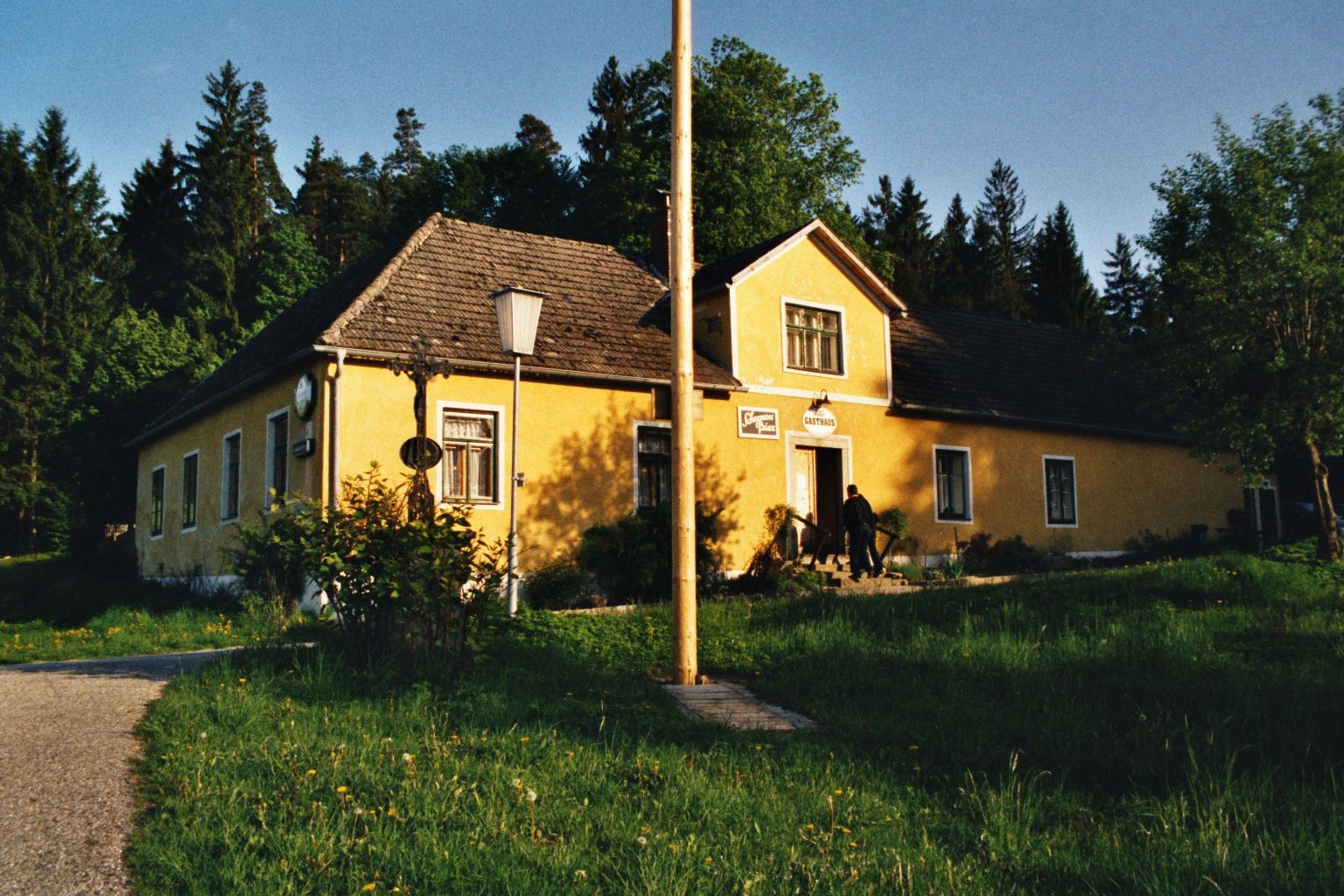 Yellow inn in a rural setting with trees in the background.