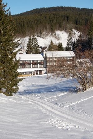 Snow-covered hotel in a mountain landscape with fir trees.