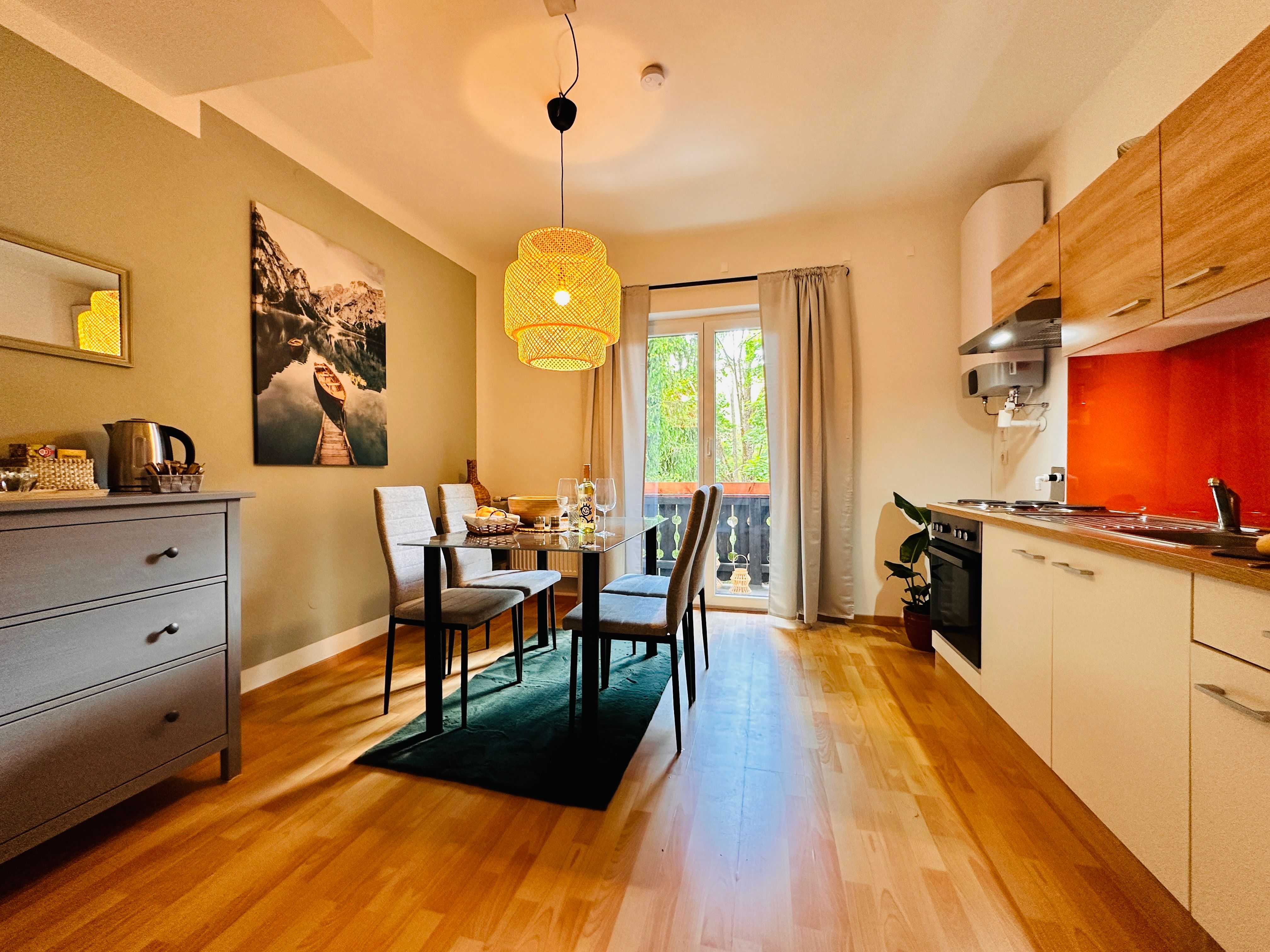 Cozy apartment with dining table, chairs, kitchenette and balcony.