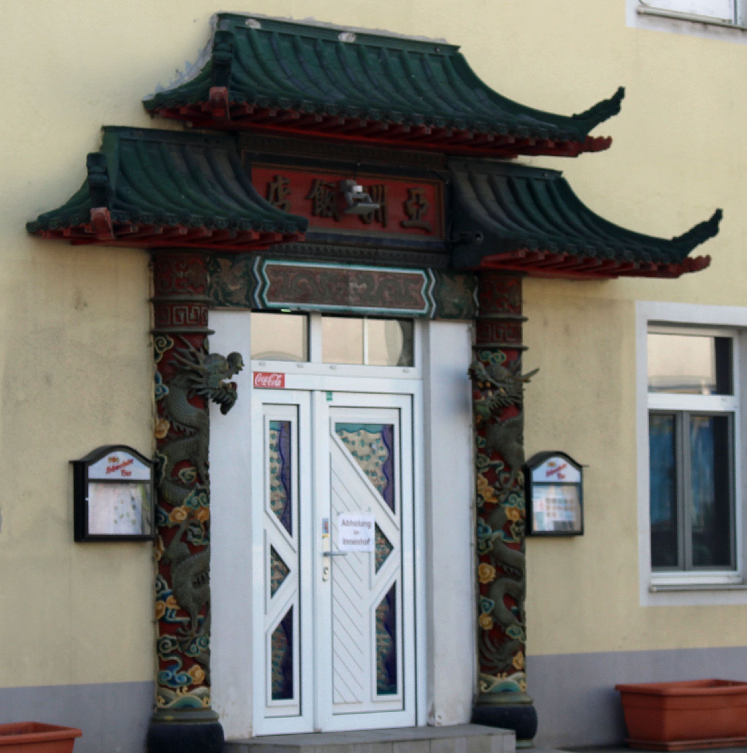 Entrance to a Chinese restaurant with a traditional Chinese roof and decorative pillars.