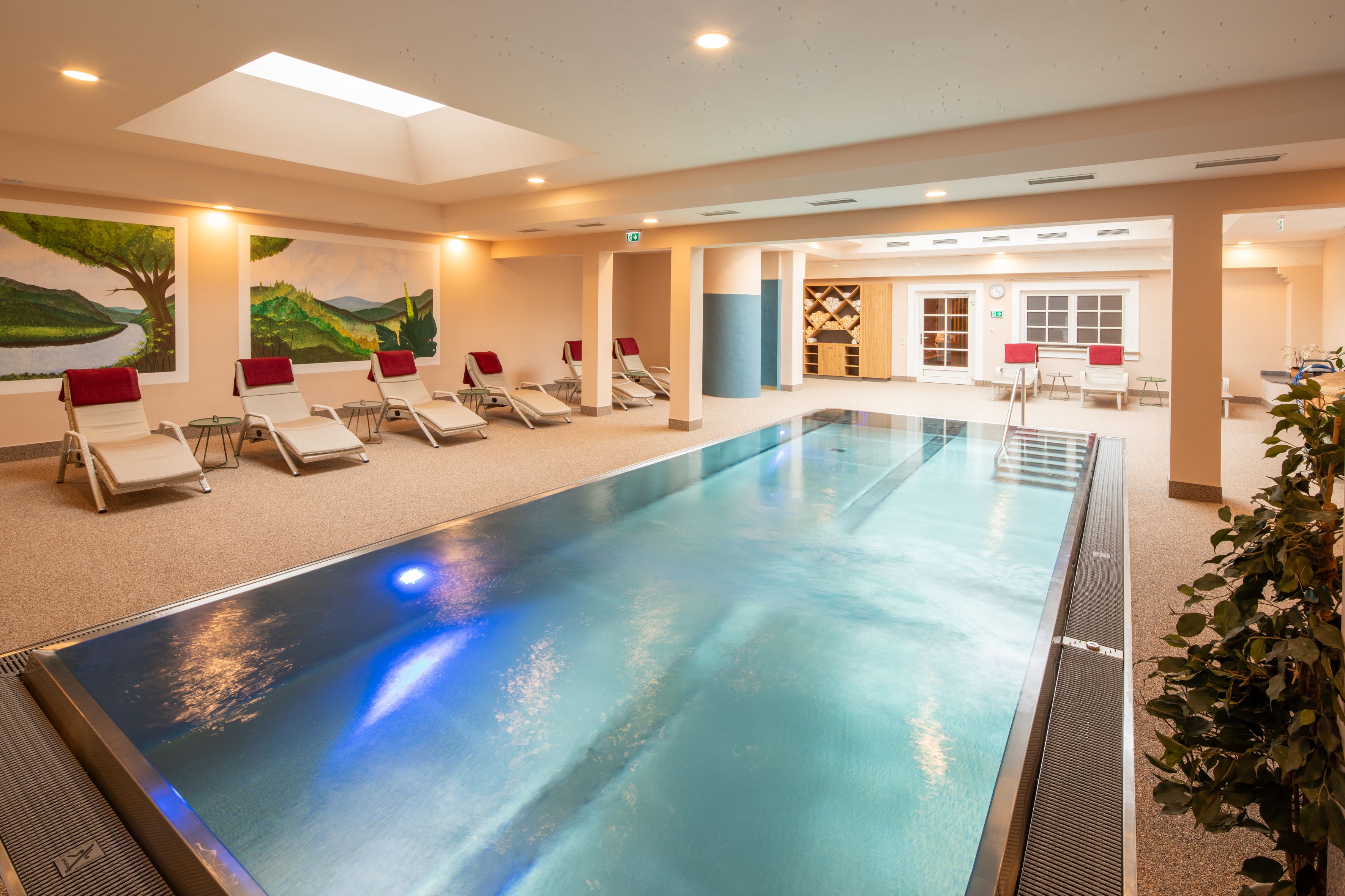 A modern indoor pool in the hotel spa with loungers and murals