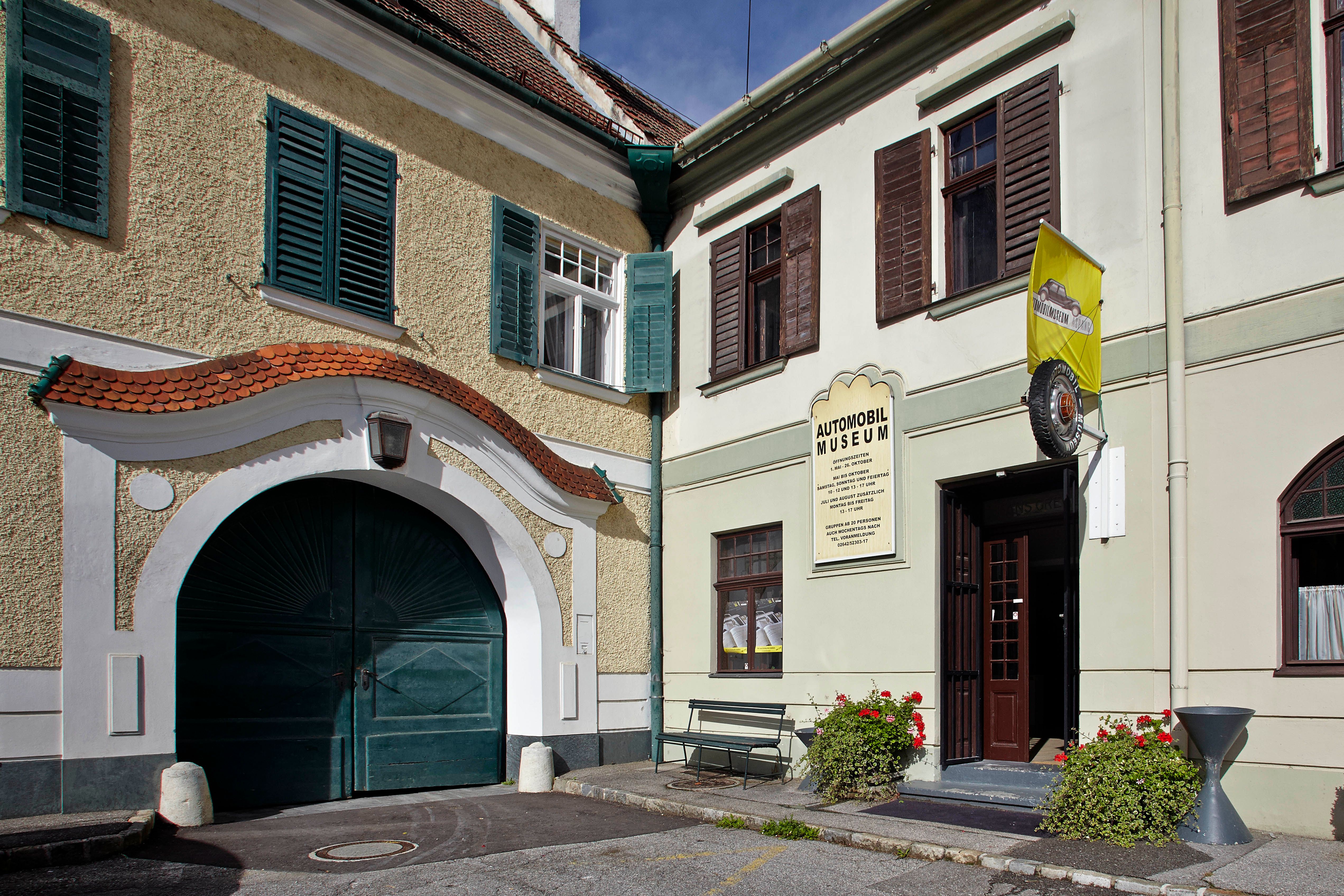 Entrance to the Aspang Markt automobile museum with yellow flag and flowers.