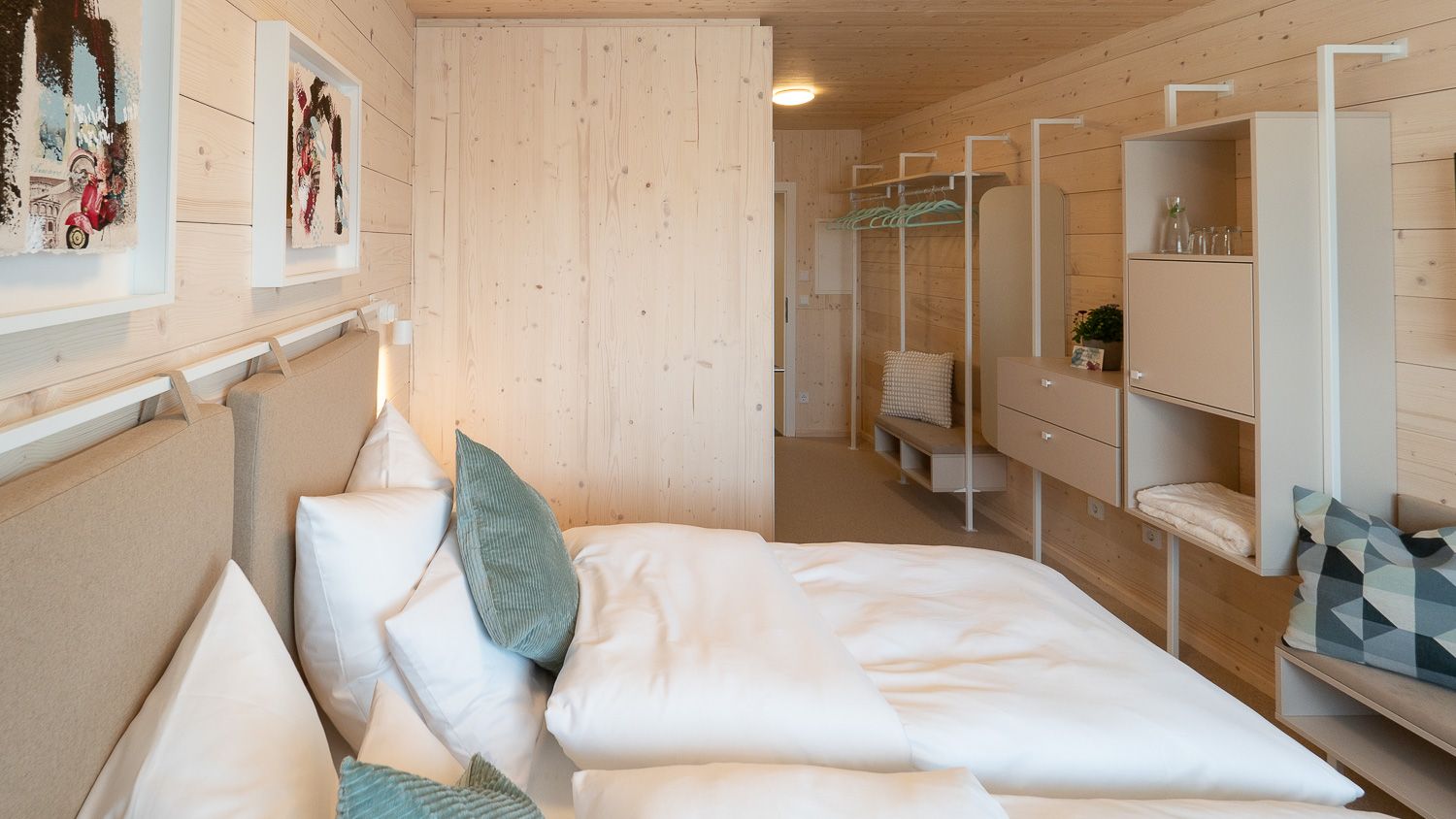 Modern double room with wooden walls, bed, pillows and minimalist furnishings.