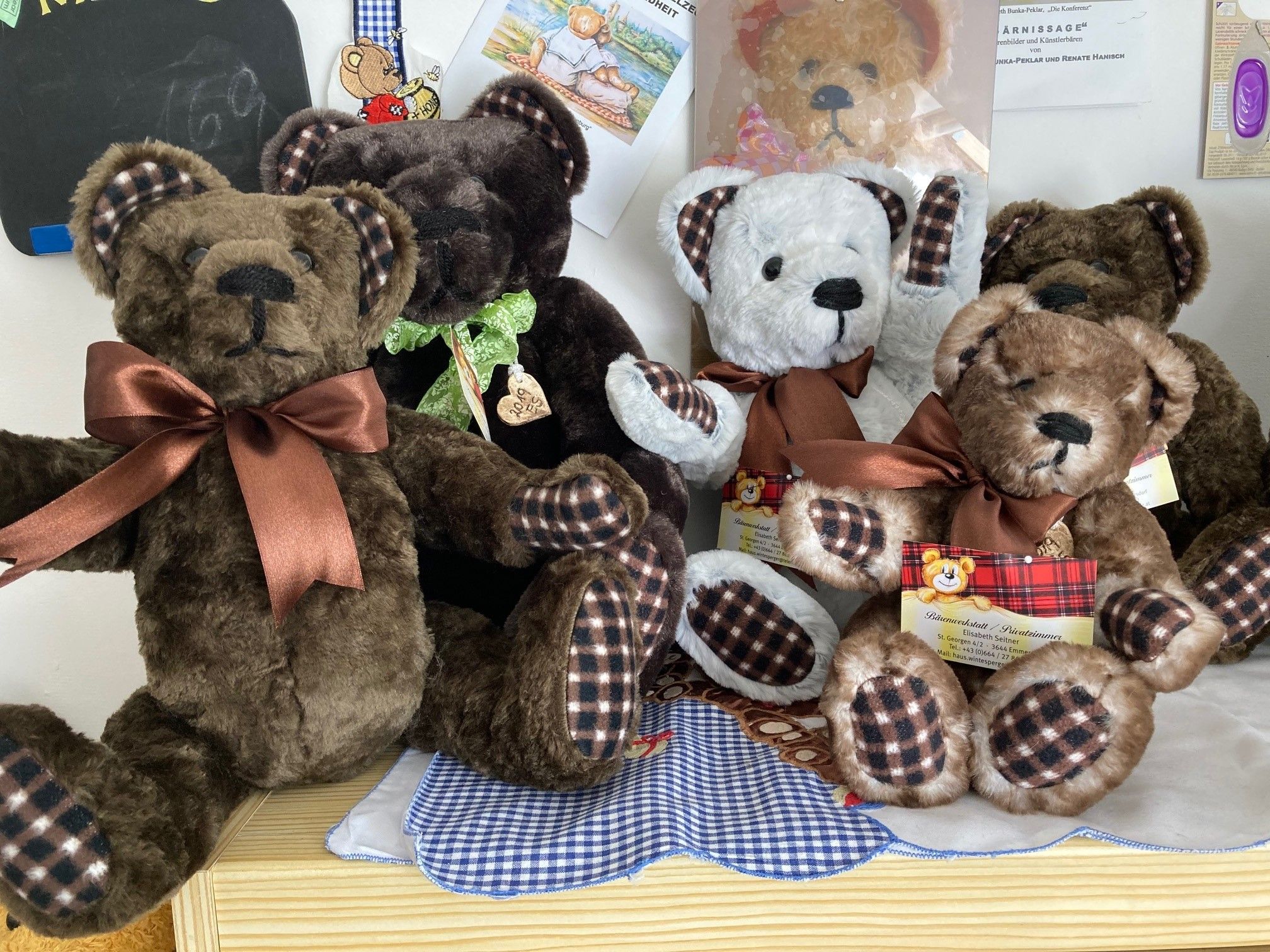 Five plush bears with bows sit on a table.