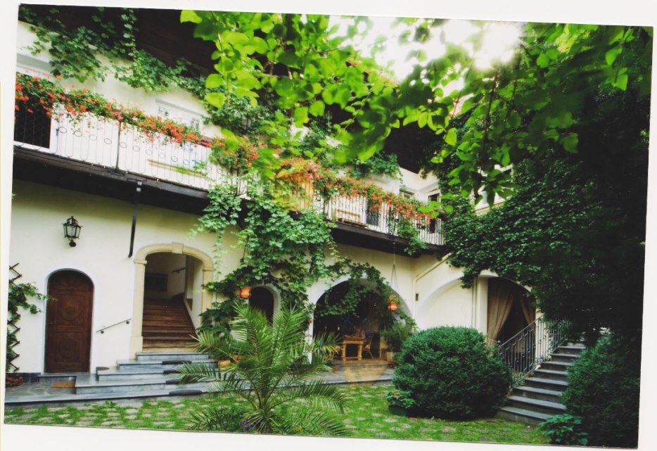 A green inner courtyard with plants and a two-storey building with balconies.