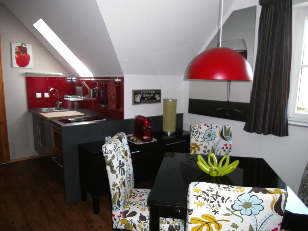 Modern kitchen with red splashback, dining table and patterned chairs.