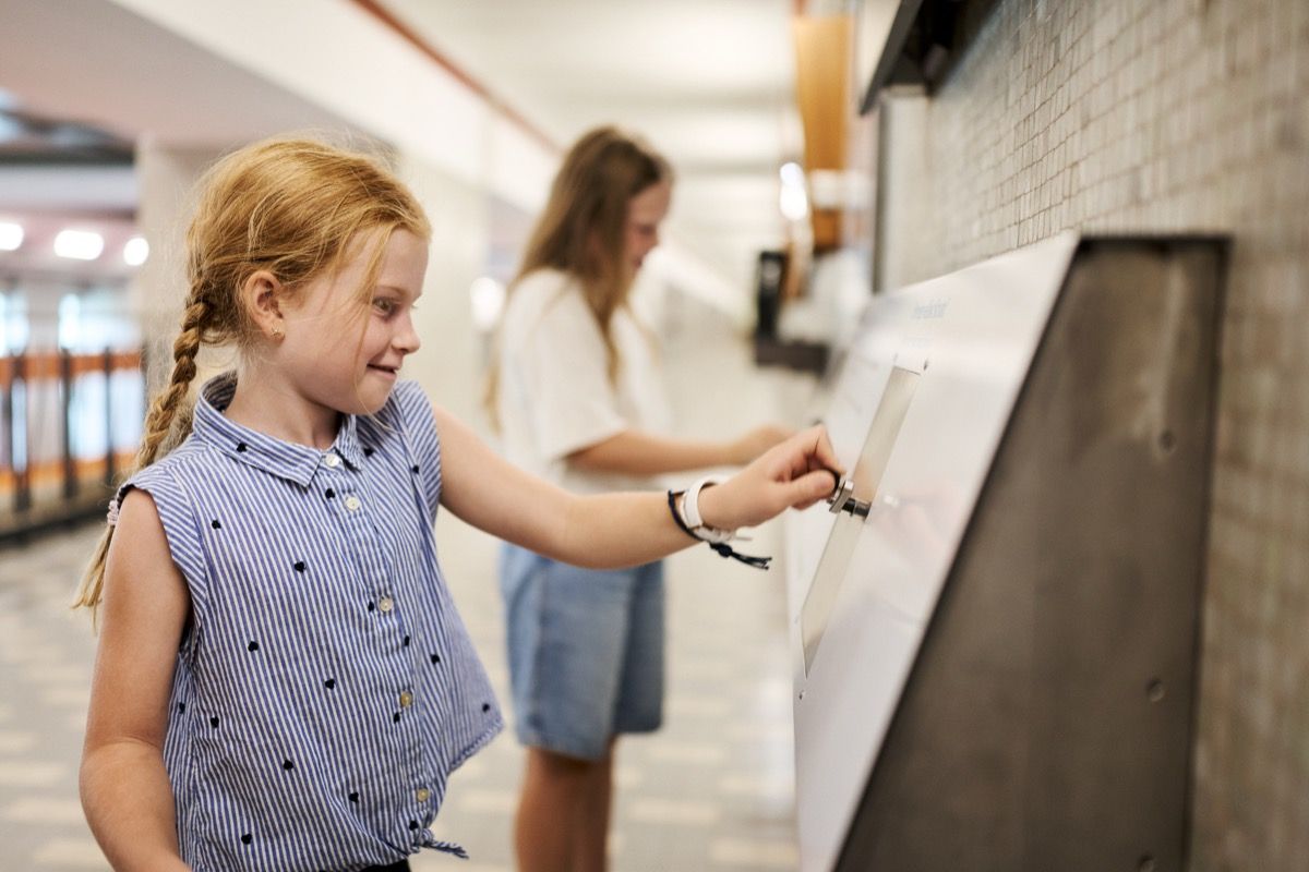 At an interactive station equipped with a crank, a magnet, and a copper coil, two girls generate electricity themselves.